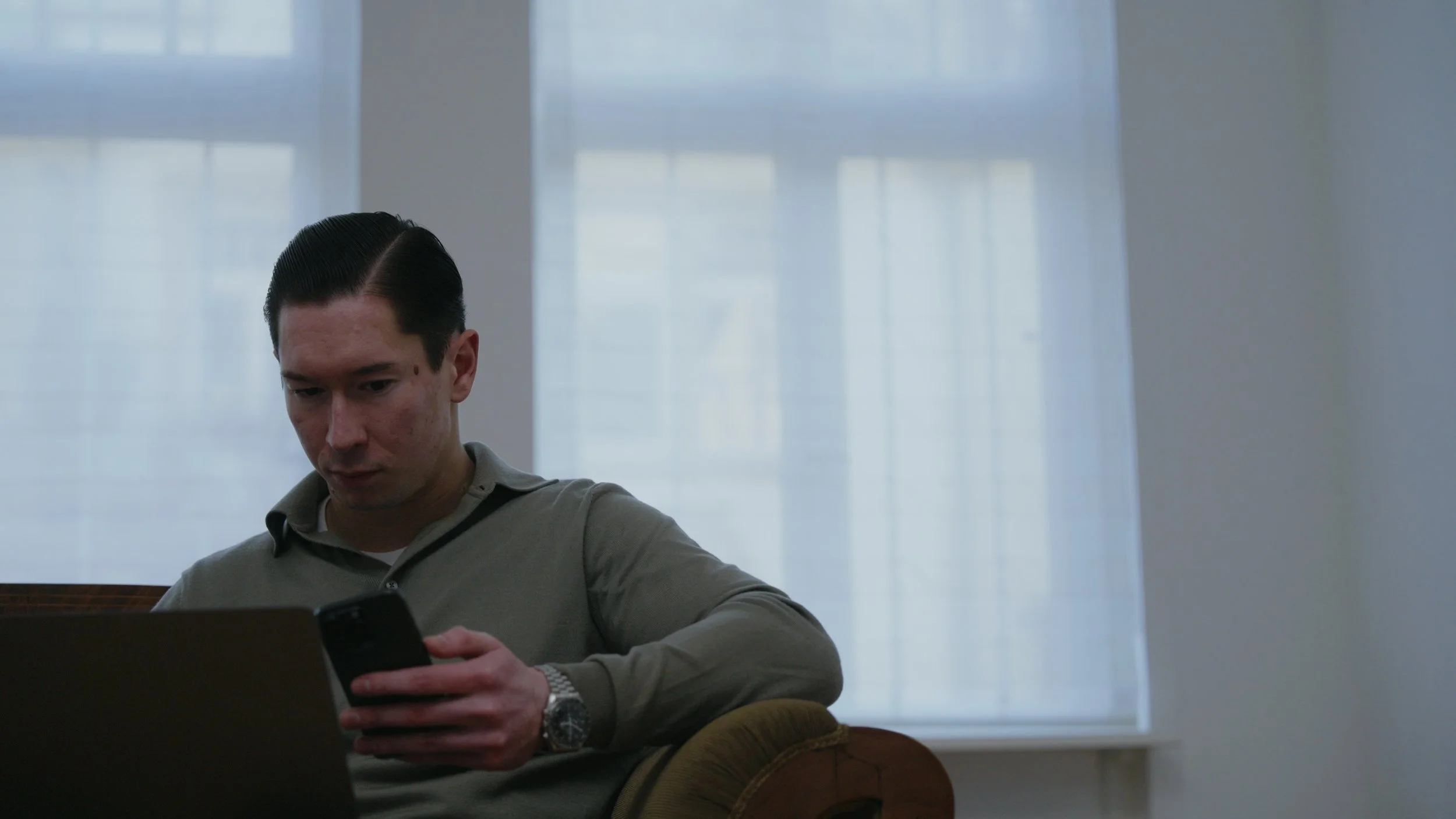 Mann sitzt auf dem Sofa und arbeitet am Handy