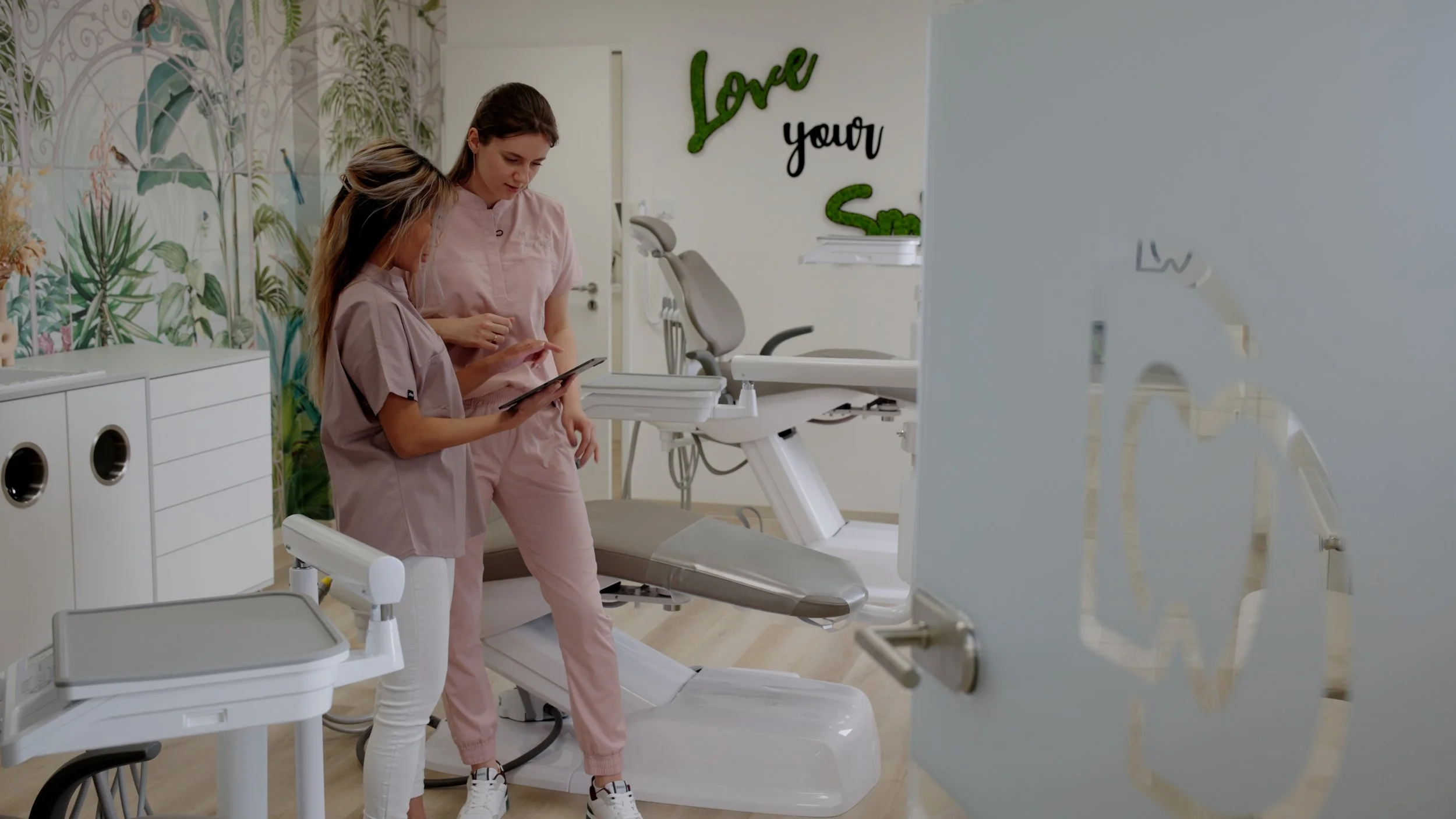 two women standing in a room, ipad in hand