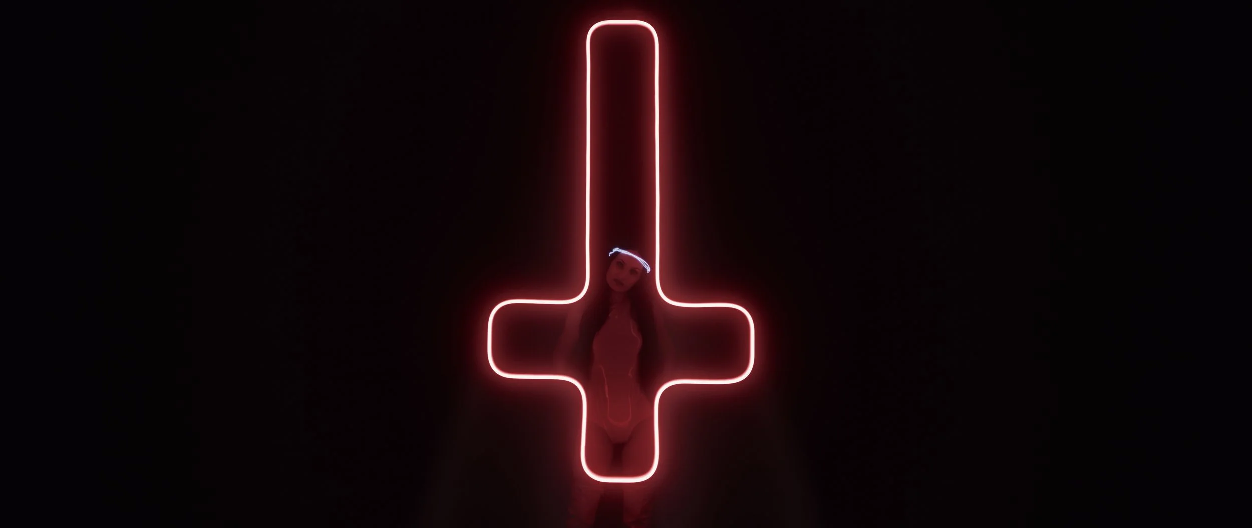 woman standing behind neon crucifix