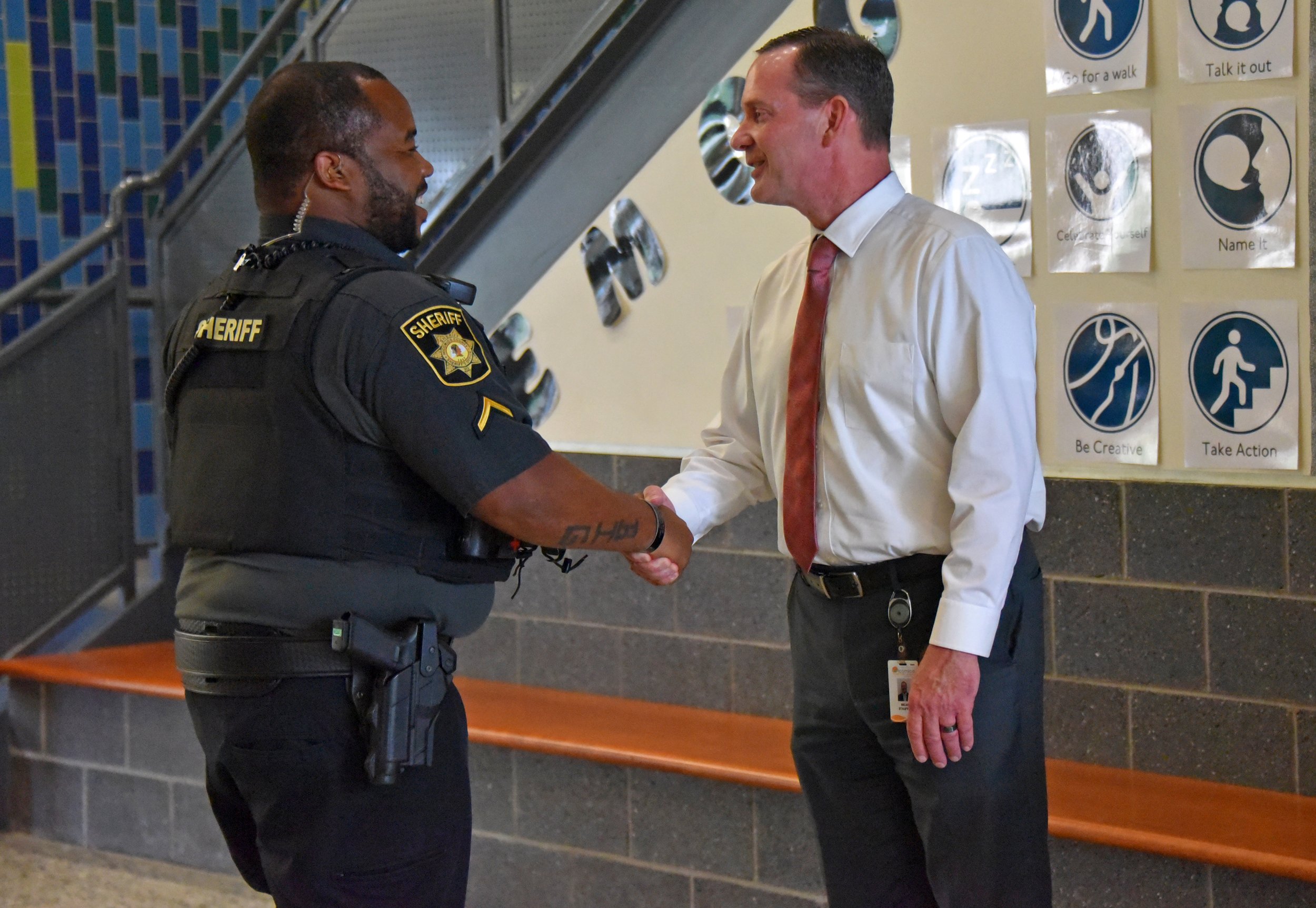 sheriffs-deputy-greeting-administrator-school-hallway.jpg