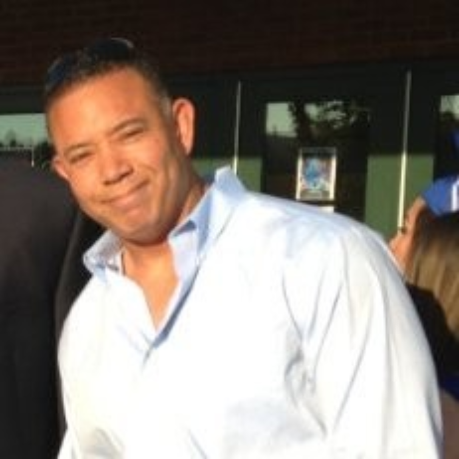 Person in a white shirt smiling outdoors, with a blurred background.