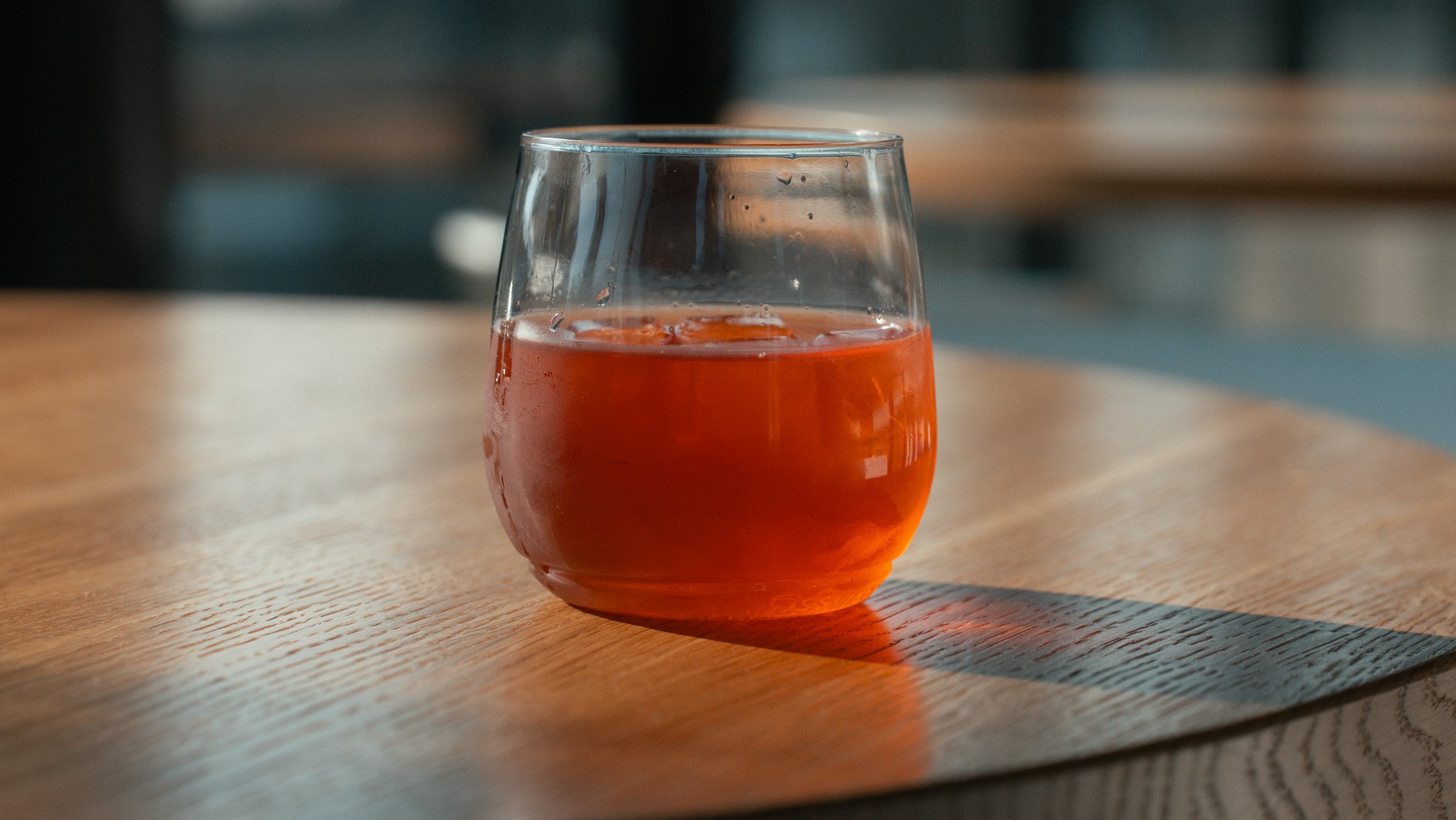 A glass of iced tea on a wooden table with sunlight shining on it.