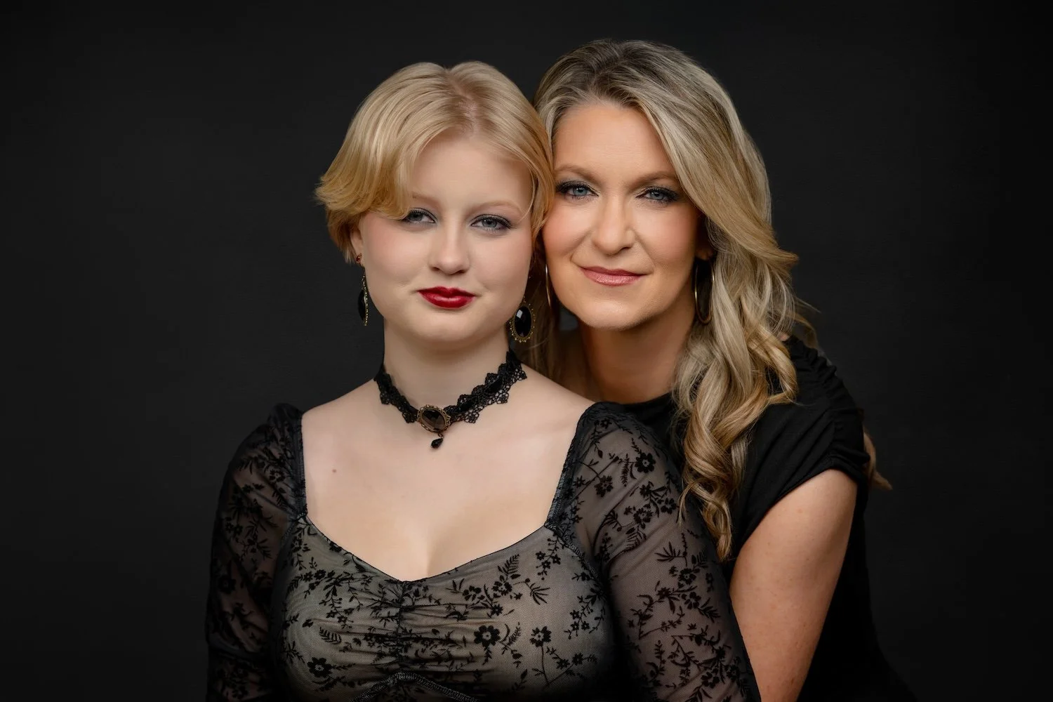 Mother and daughter posing closely together in black outfits