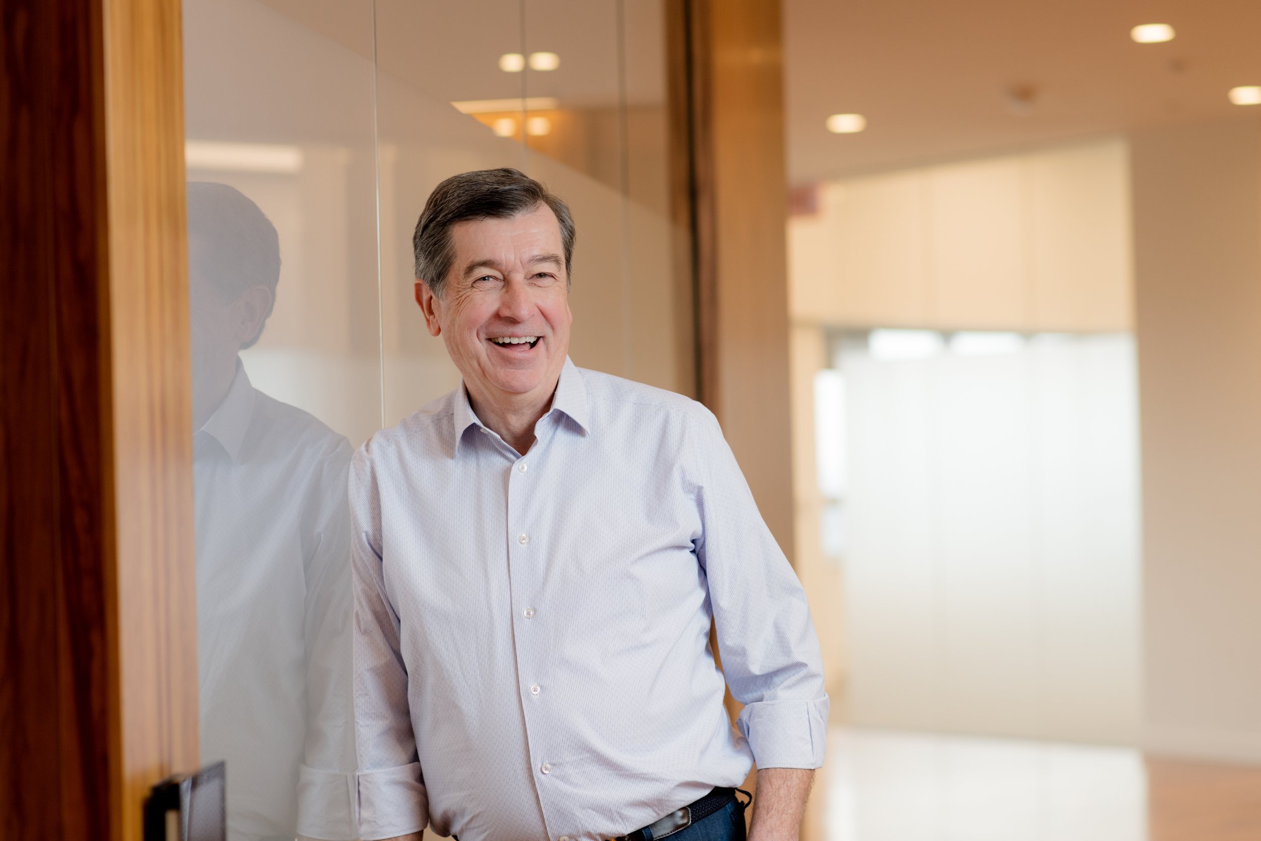Smiling businessman in a tailored vest and open-collar shirt, his demeanor friendly and inviting as he poses for the camera.