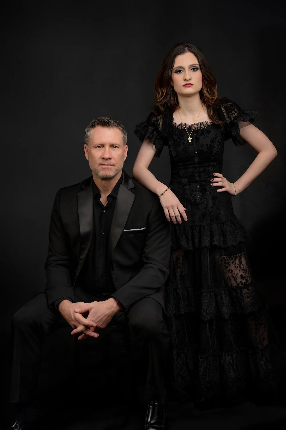 Father seated beside his daughter in coordinated black formalwear