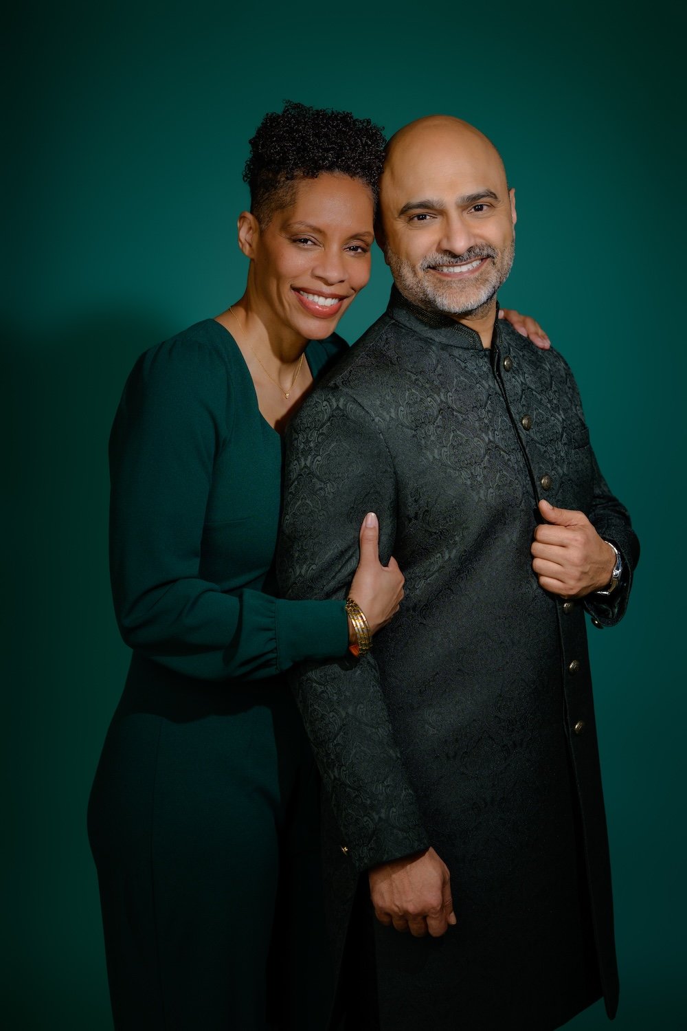 Smiling couple posing together in coordinated green and black outfits