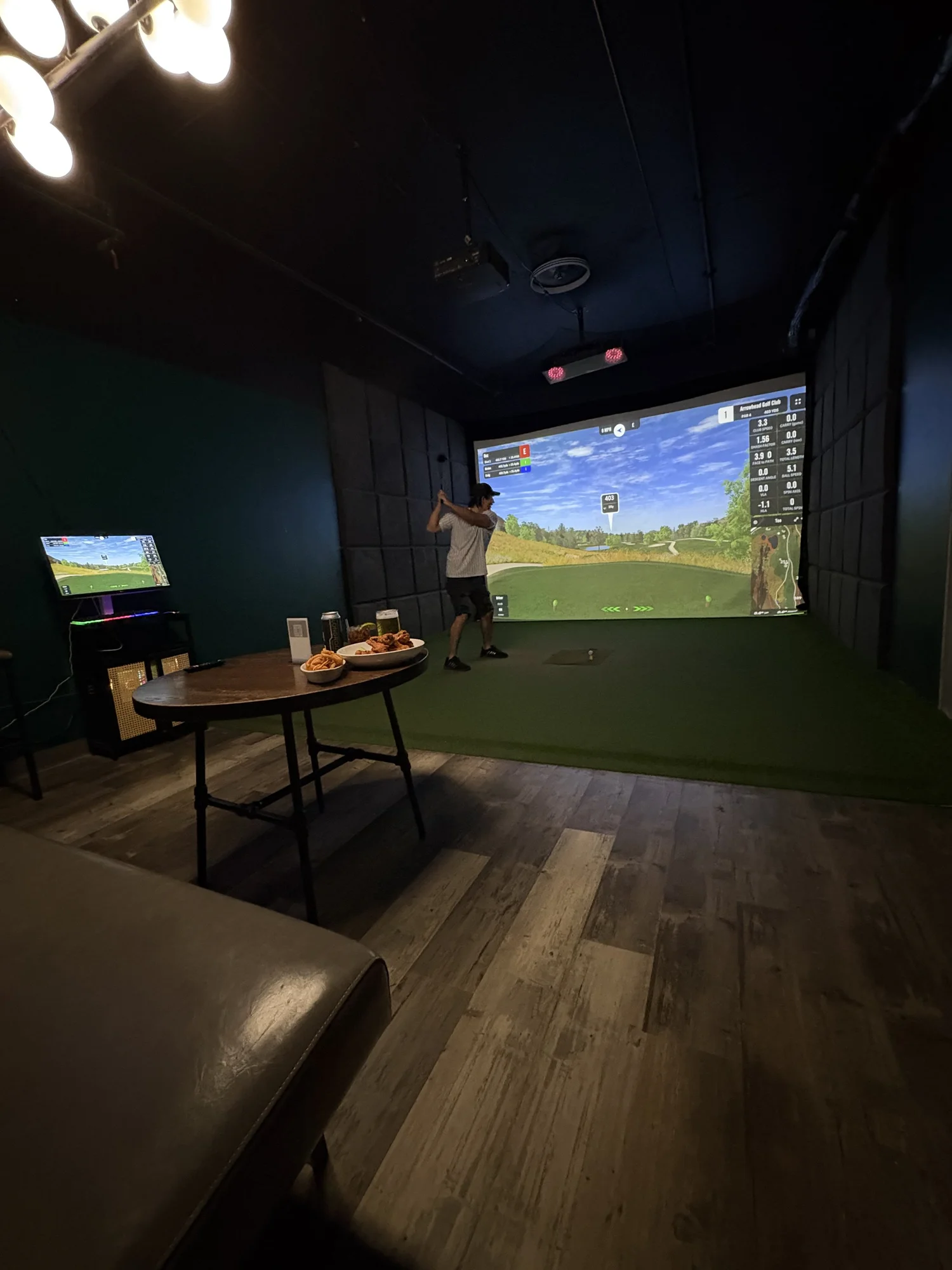 Golfer teeing off in a private simulator room at Albatross Virtual Golf