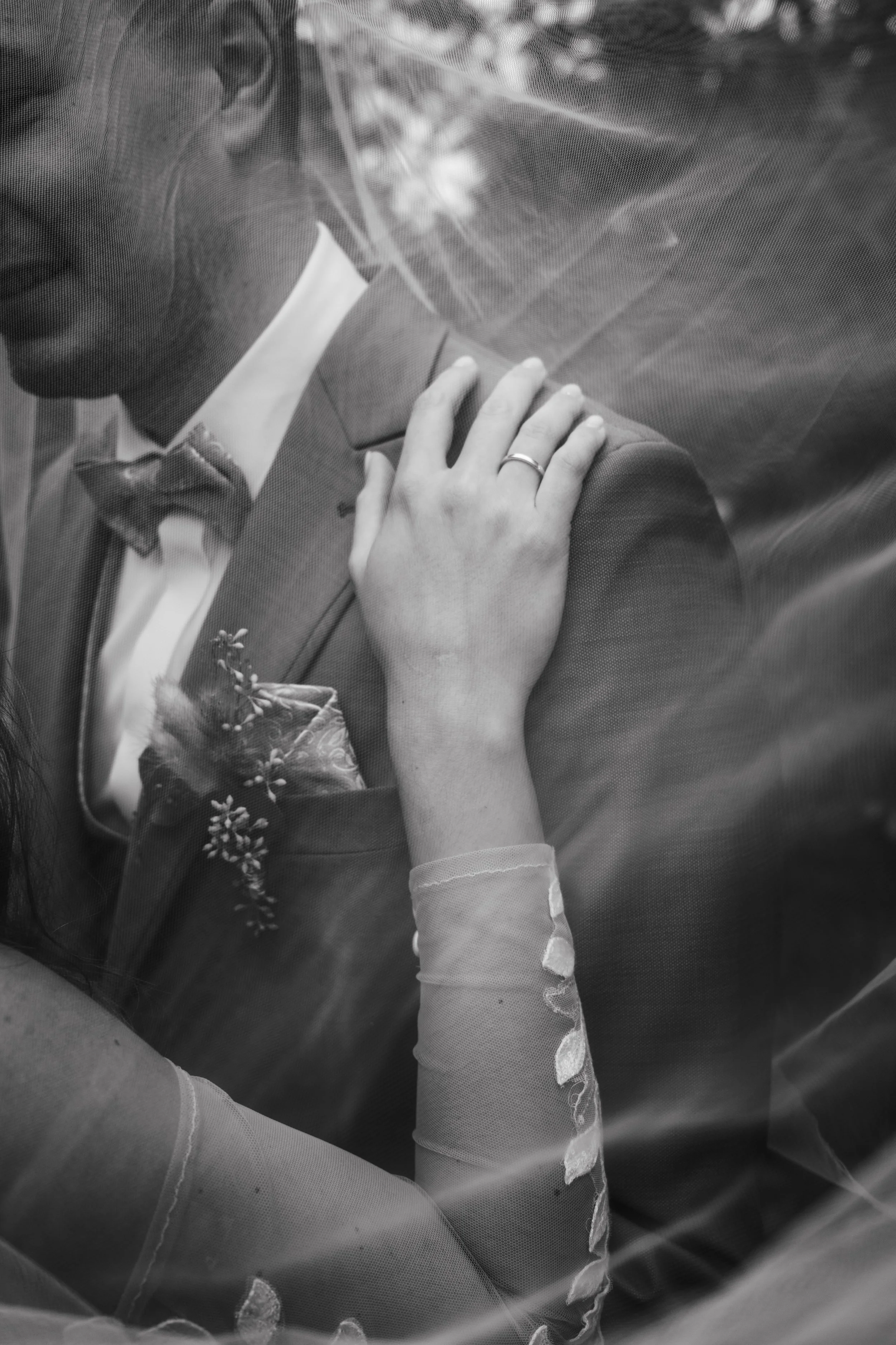 Ein Brautpaar, das sich während der Hochzeit küsst, nur teilweise sichtbar durch einen Schleier. Es ist eine schwarz-weiße Nahaufnahme.