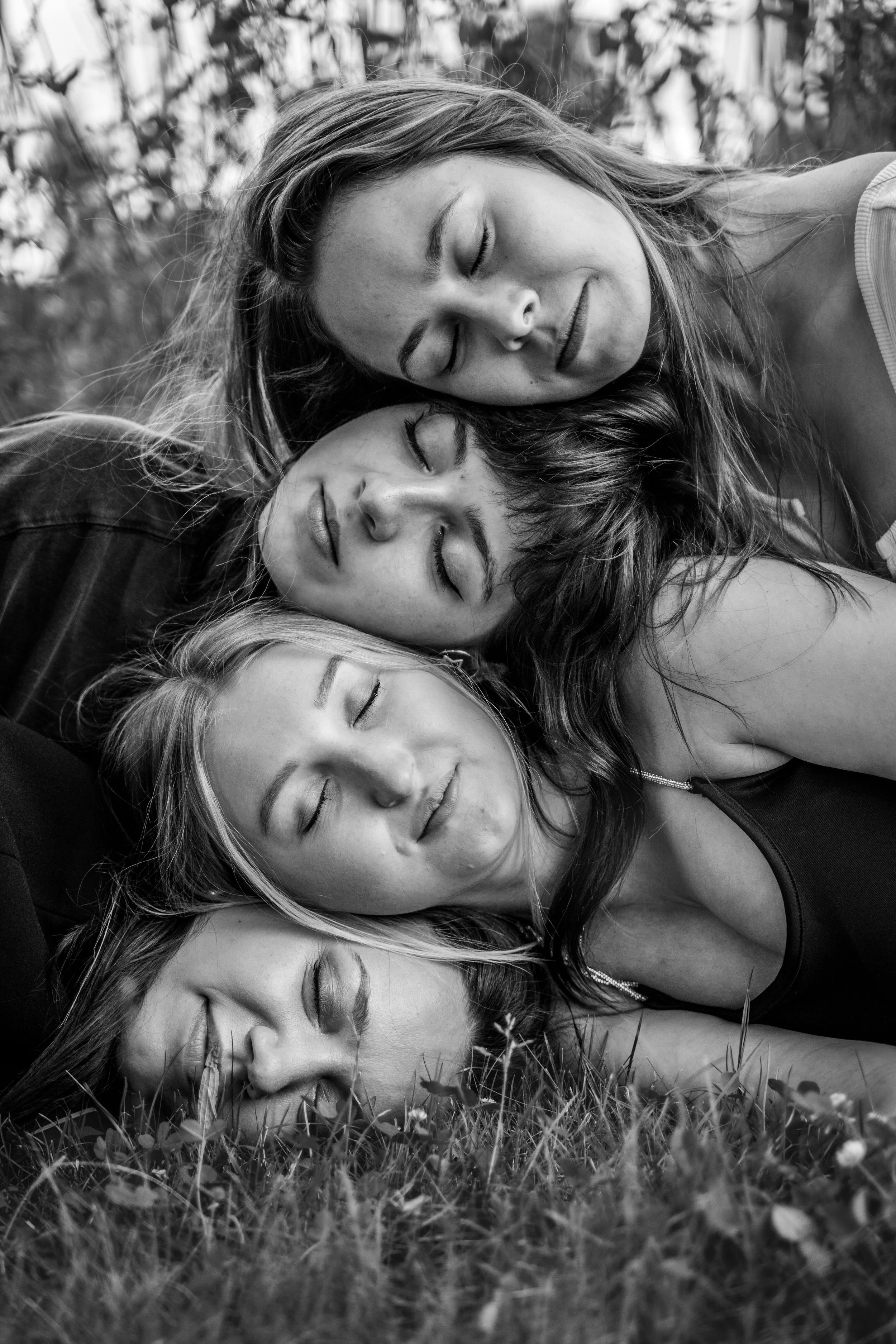 Vier junge Frauen schlafen auf der Wiese, alle haben die Augen geschlossen und liegen eng beieinander.