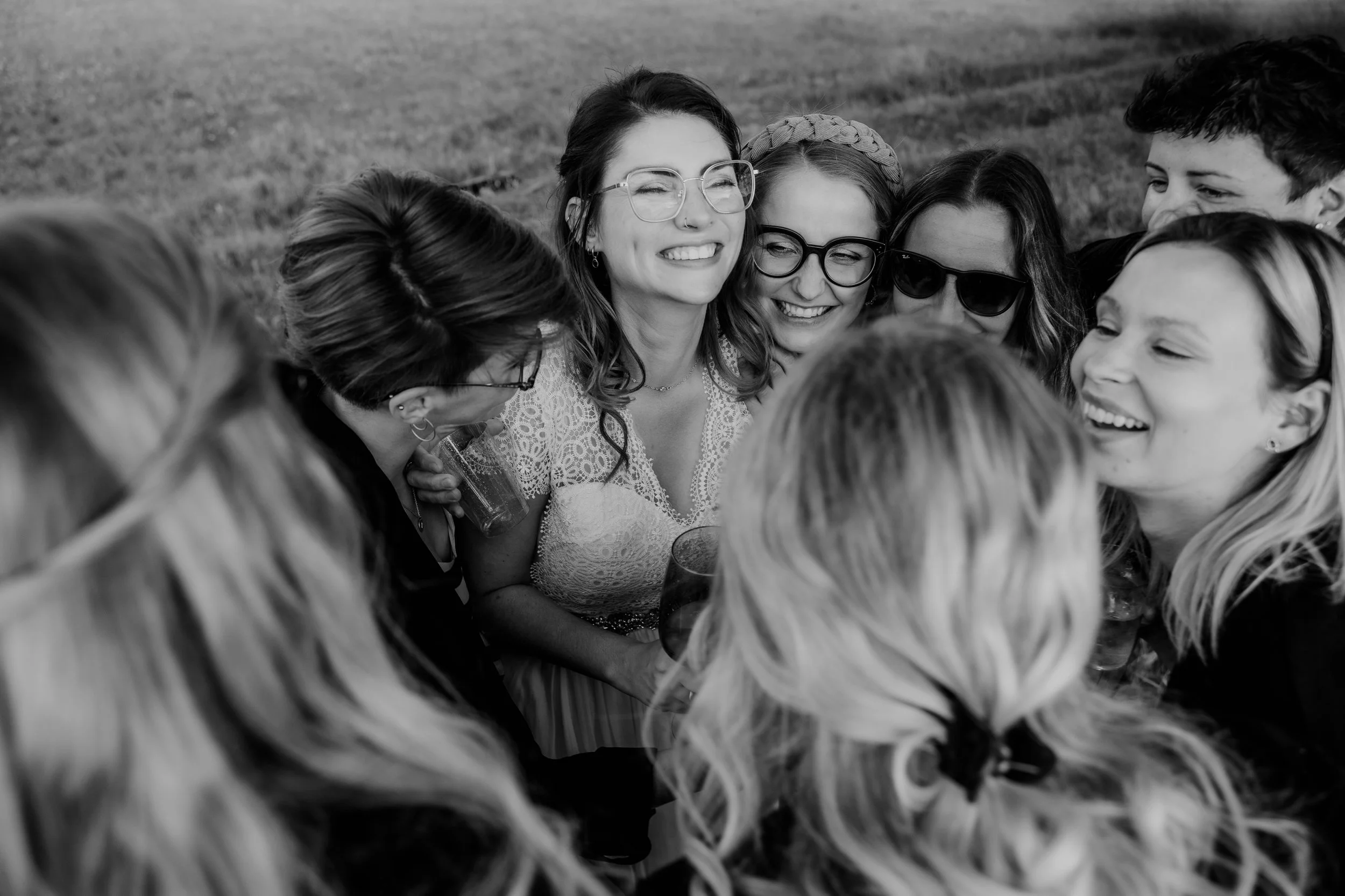 Gruppe lachender Menschen im Kreis bei einem Treffen im Freien, schwarz-weiß Foto.