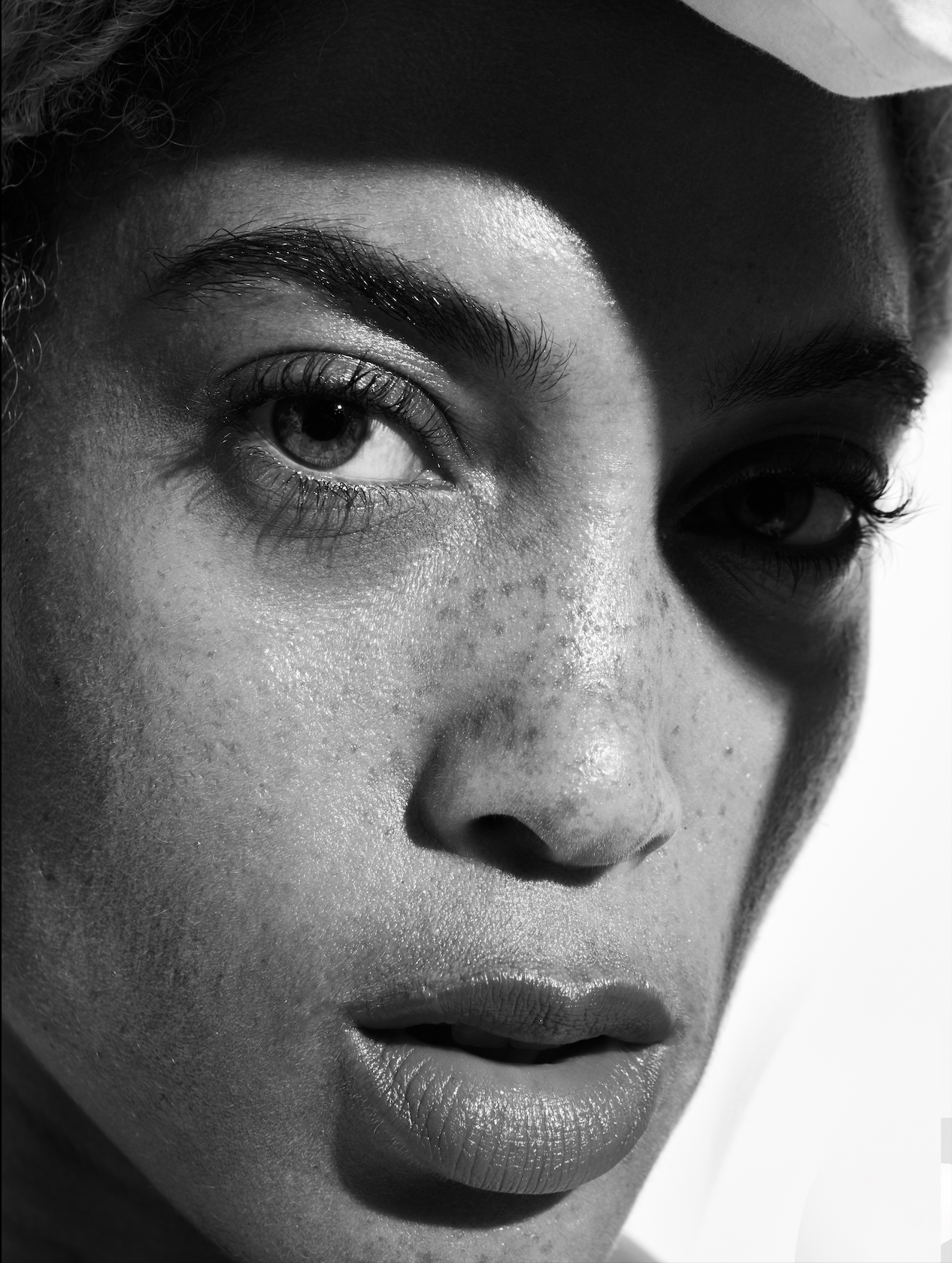 Close-up black and white photograph of a person's face, showing the eyes, nose, and lips with detailed skin texture and hair.