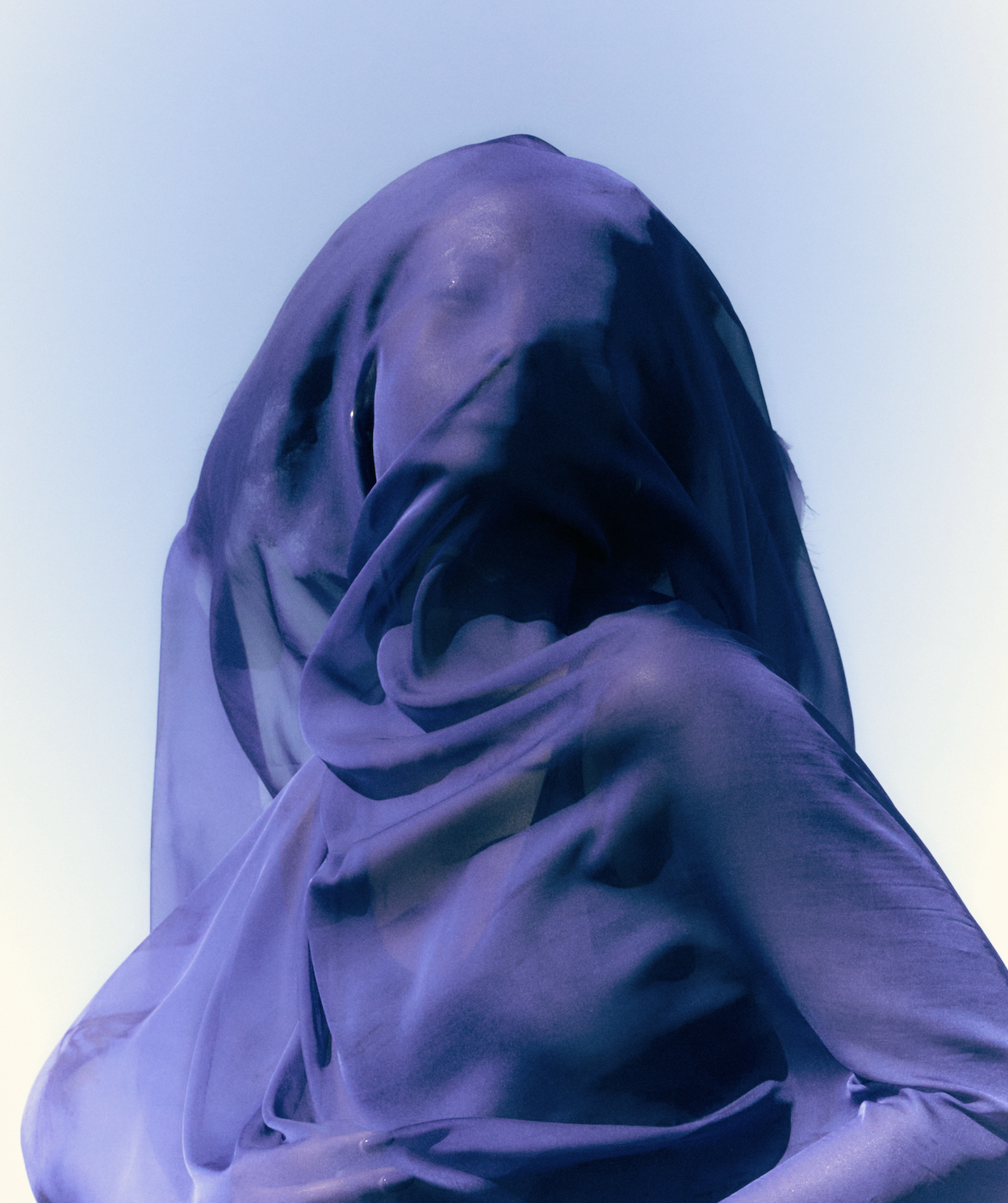 A person dressed in a blue hooded fabric with blurred facial features.