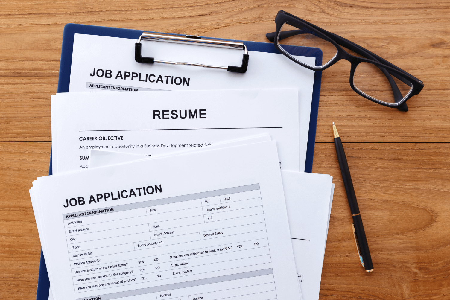 Clipboard displaying a job application and resume, organized for review.