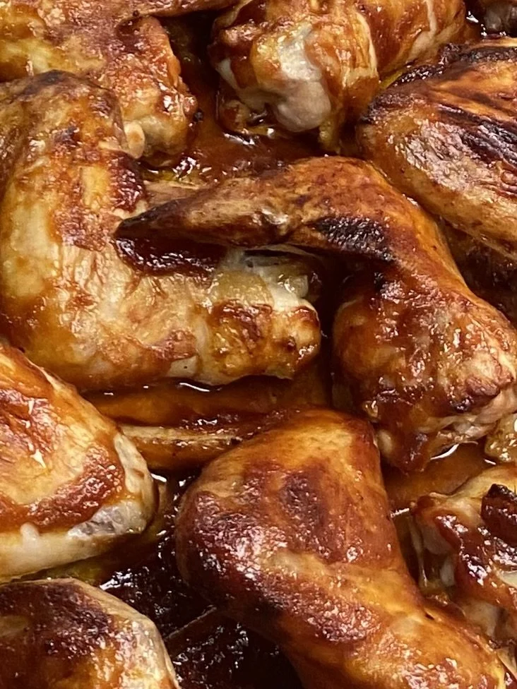 Close-up of cooked chicken drumsticks with crispy, golden-brown skin and a glaze.