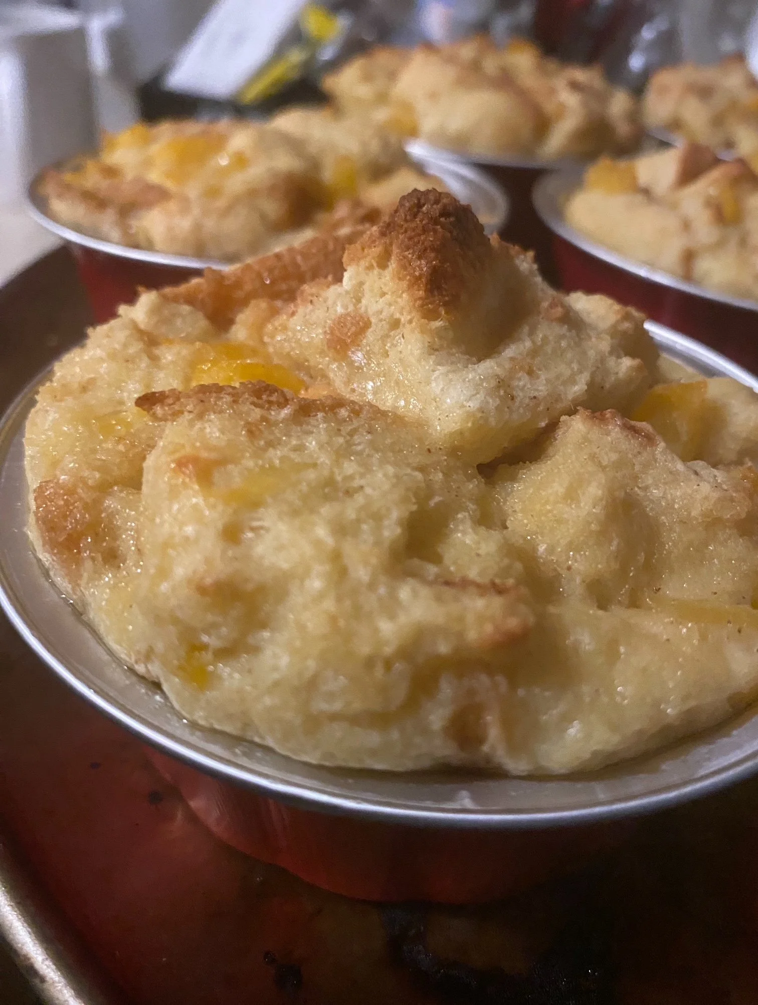Close-up of a bowl of potato casserole with a golden, crispy topping, with similar bowls of casserole in the background.