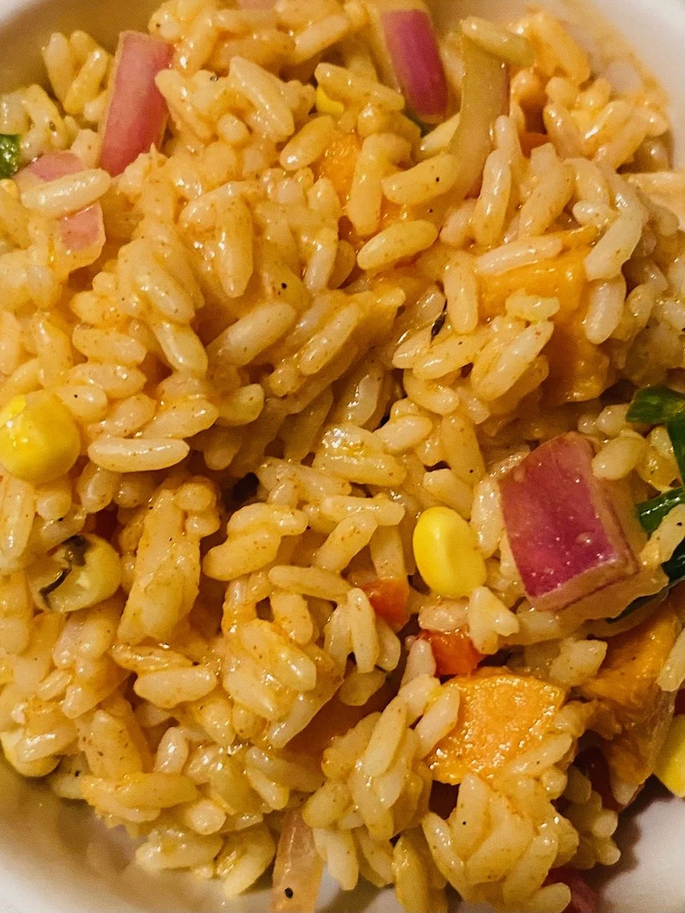 Close-up of homemade fried rice with diced ham, corn, carrots, and green onions.