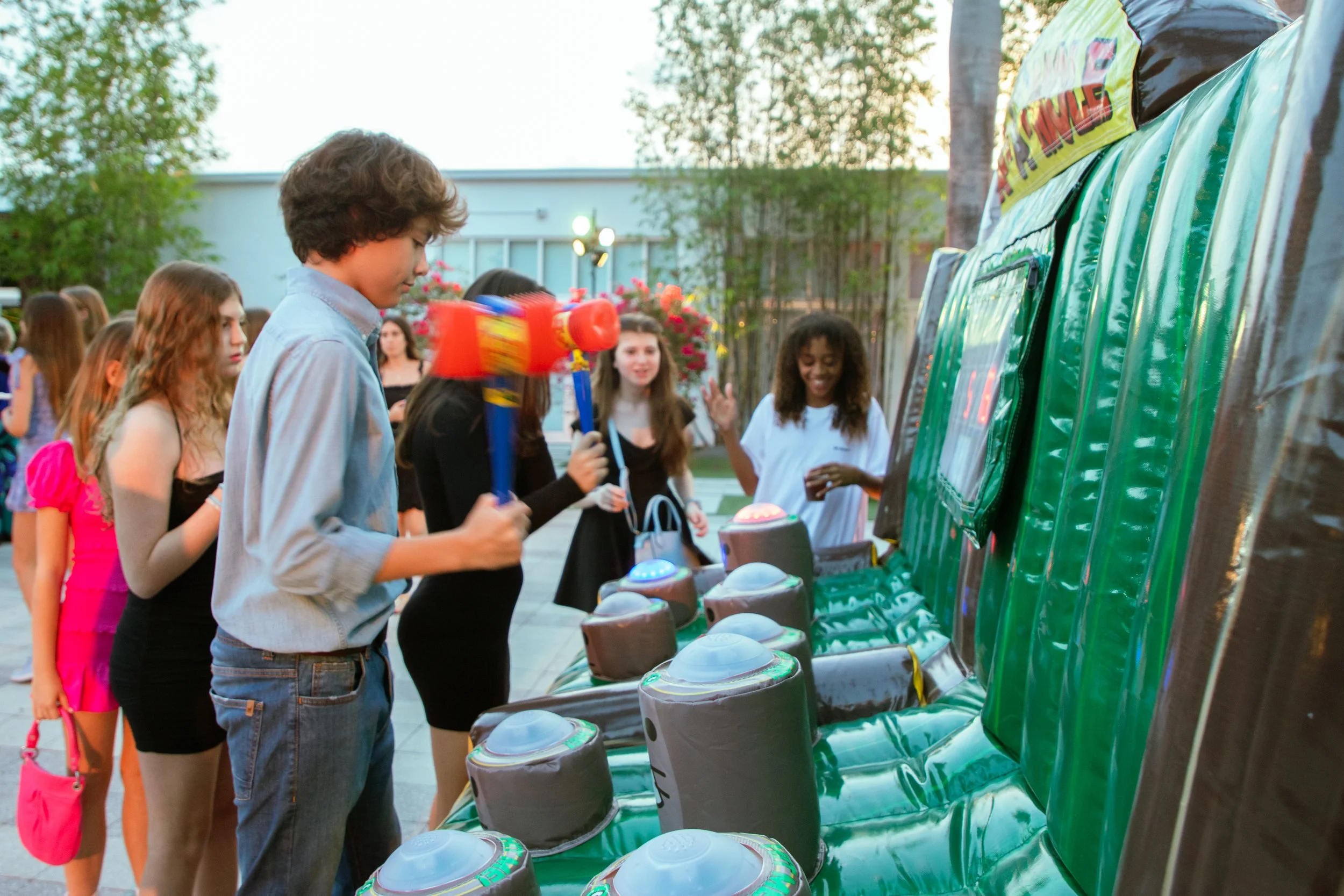 A person ready to strike a mole with a mallet in the inflatable Zap A Mole game by Fotoboyz Events, highlighting the interactive fun at an outdoor event.