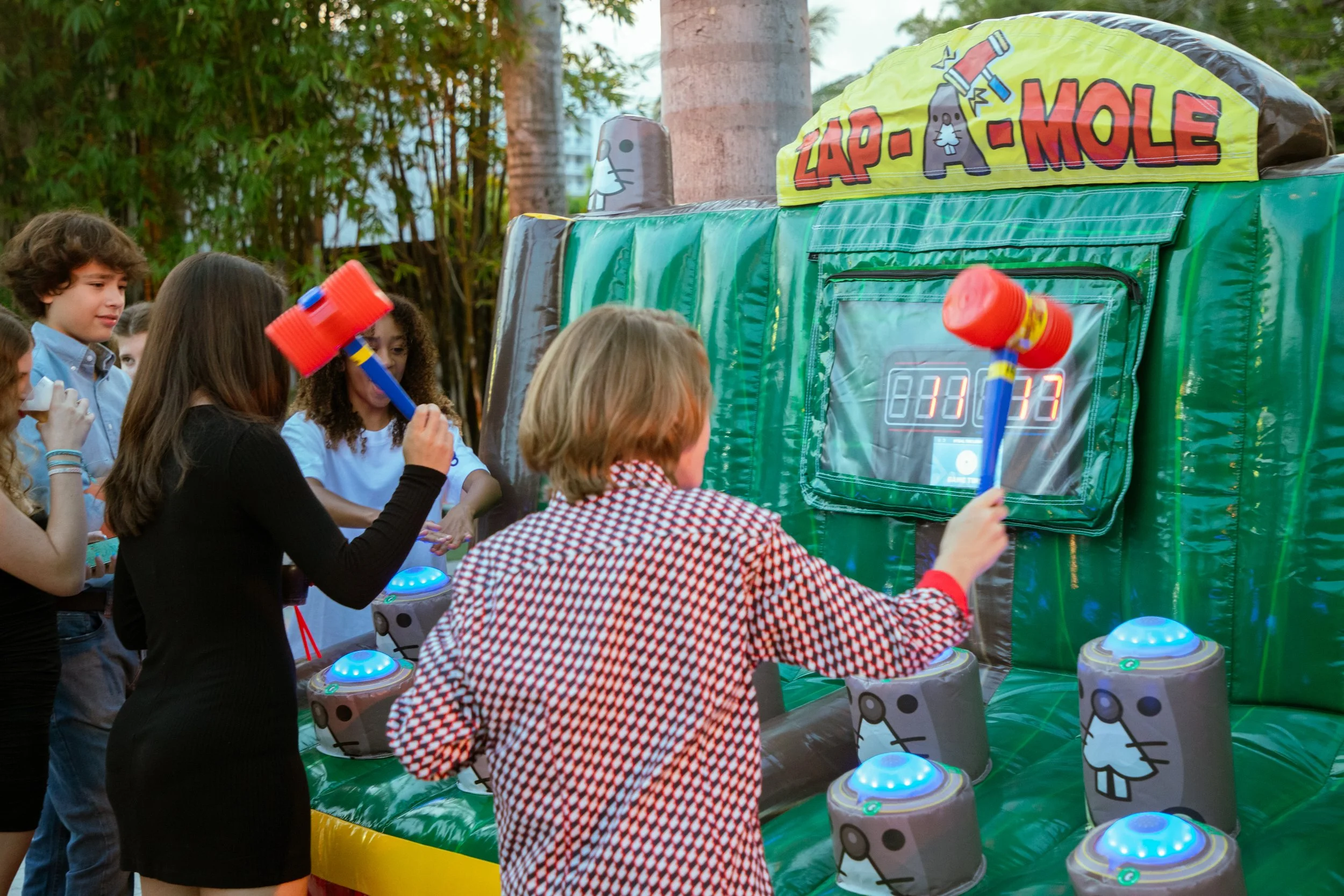 Young players competing in the inflatable Zap A Mole game by Fotoboyz Events, focusing on the scoreboard and the lively atmosphere.