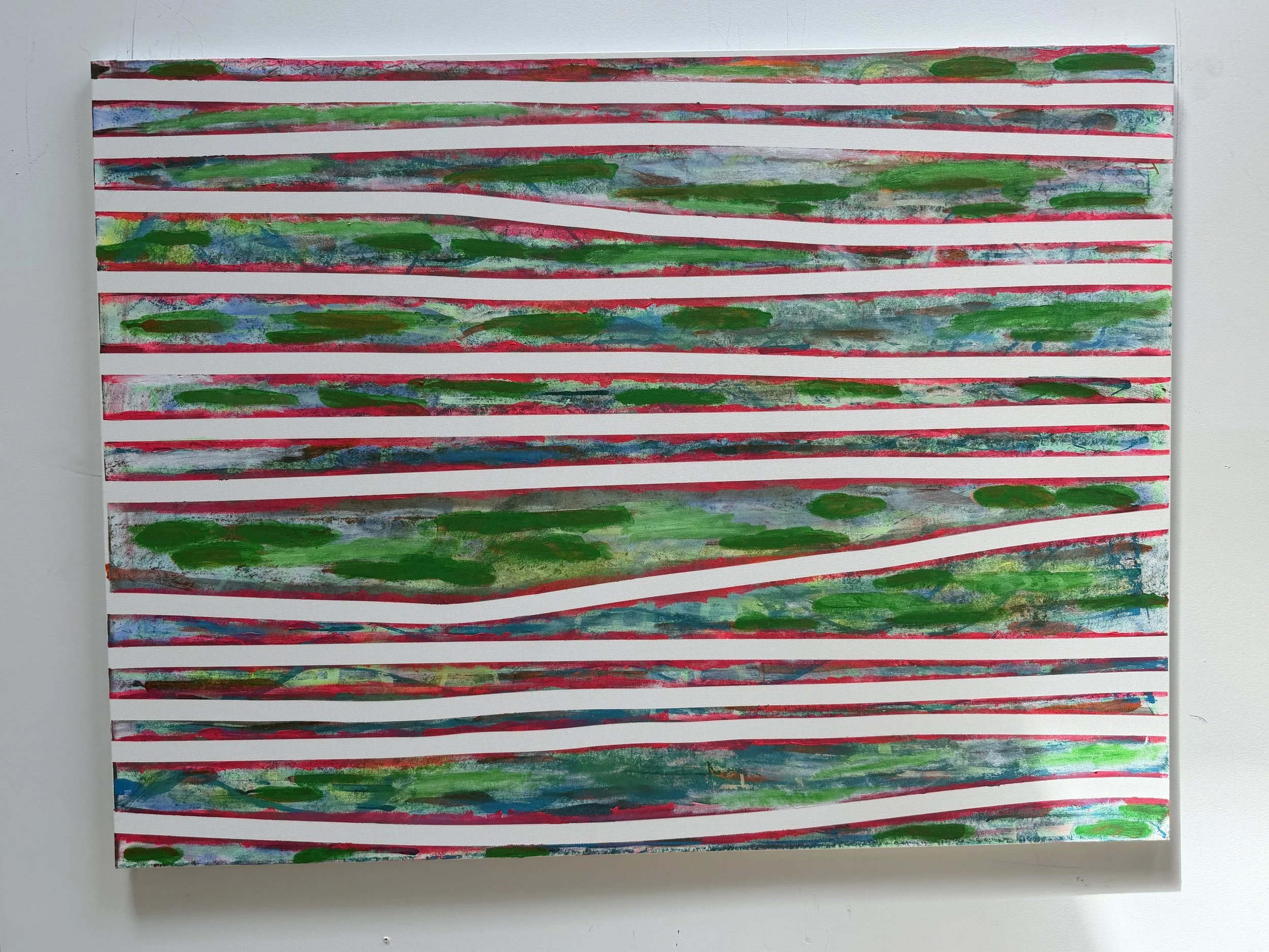 Colorful abstract painting with horizontal stripes of green, red, and blue hues, on a white canvas displayed on a white wall.