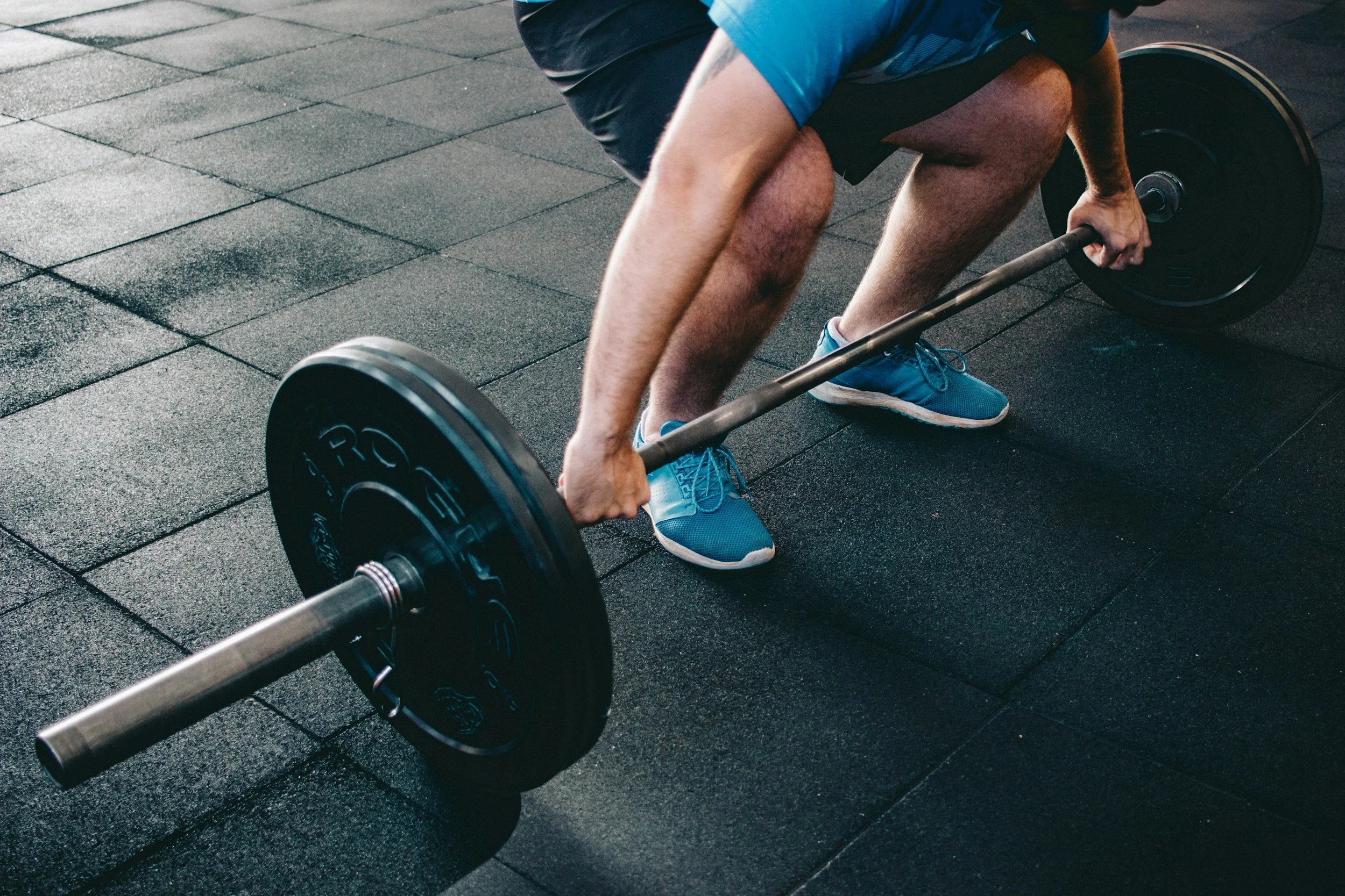 Person lifting a barbell with weights in a gym.