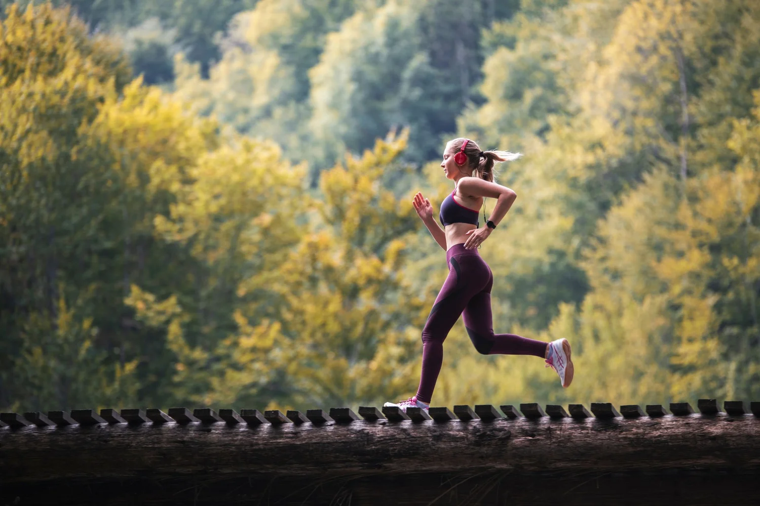 A woman running on a tree-lined trail, representing regenerative recovery