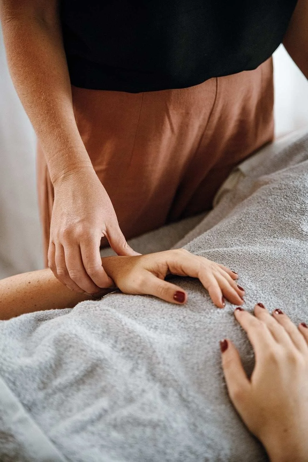 An acupuncturist takes the pulse of a patient laying on the treatment table. Pulse diagnosis is a part of TCM.