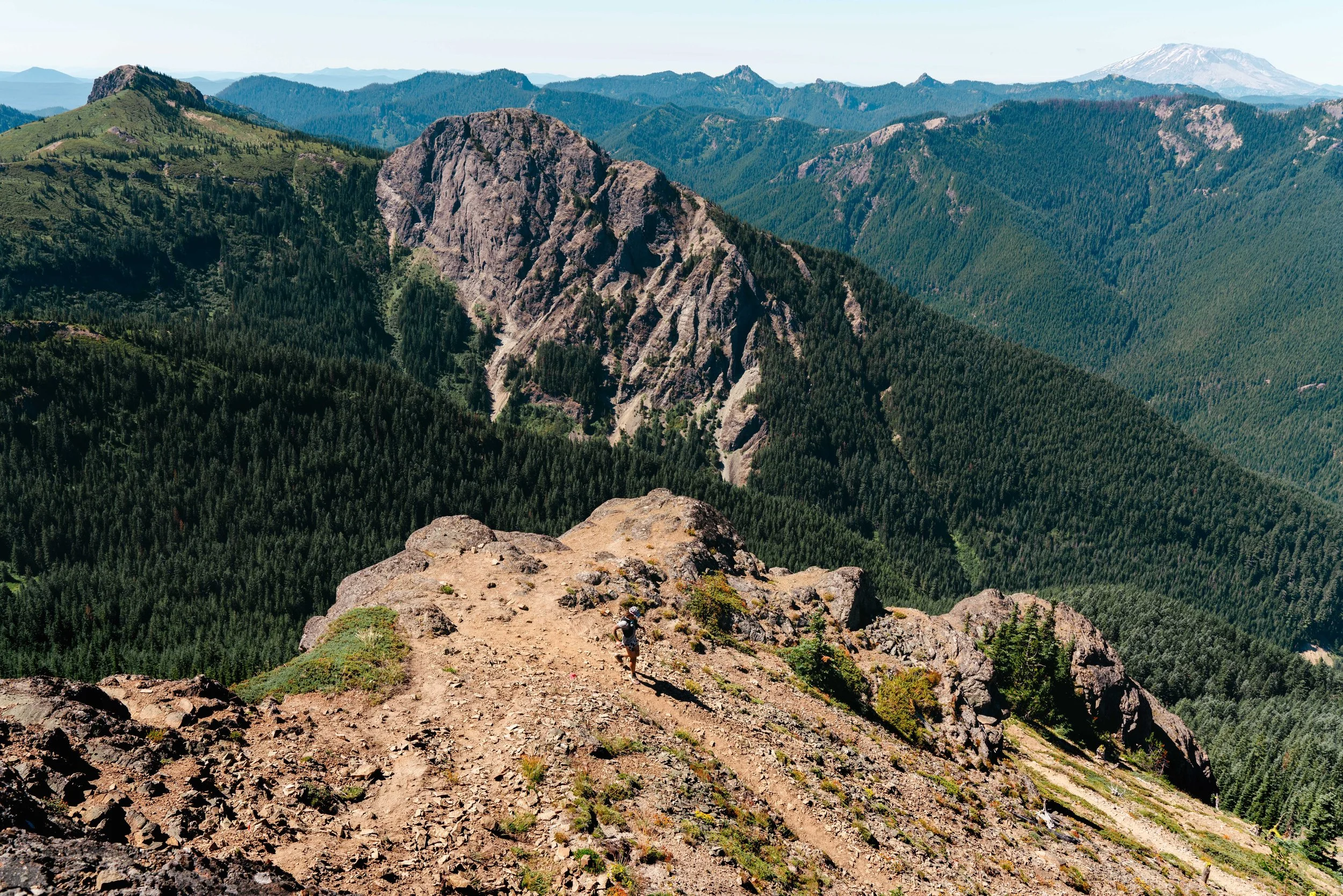 Runner descending Sunrise Peak with the Cascades in the background