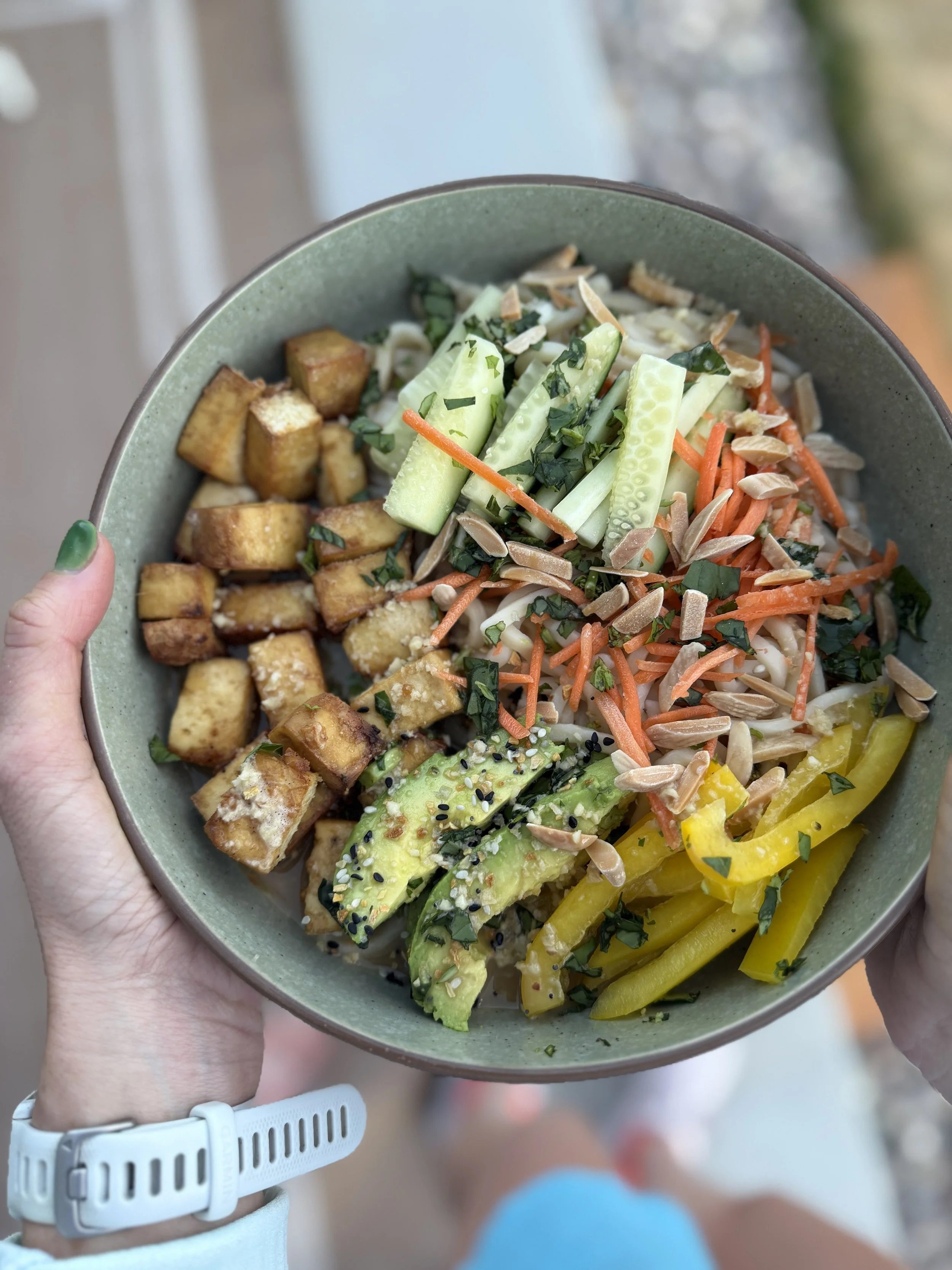 bowl with noodles, tofu, cucumber, peppers, carrots and nuts