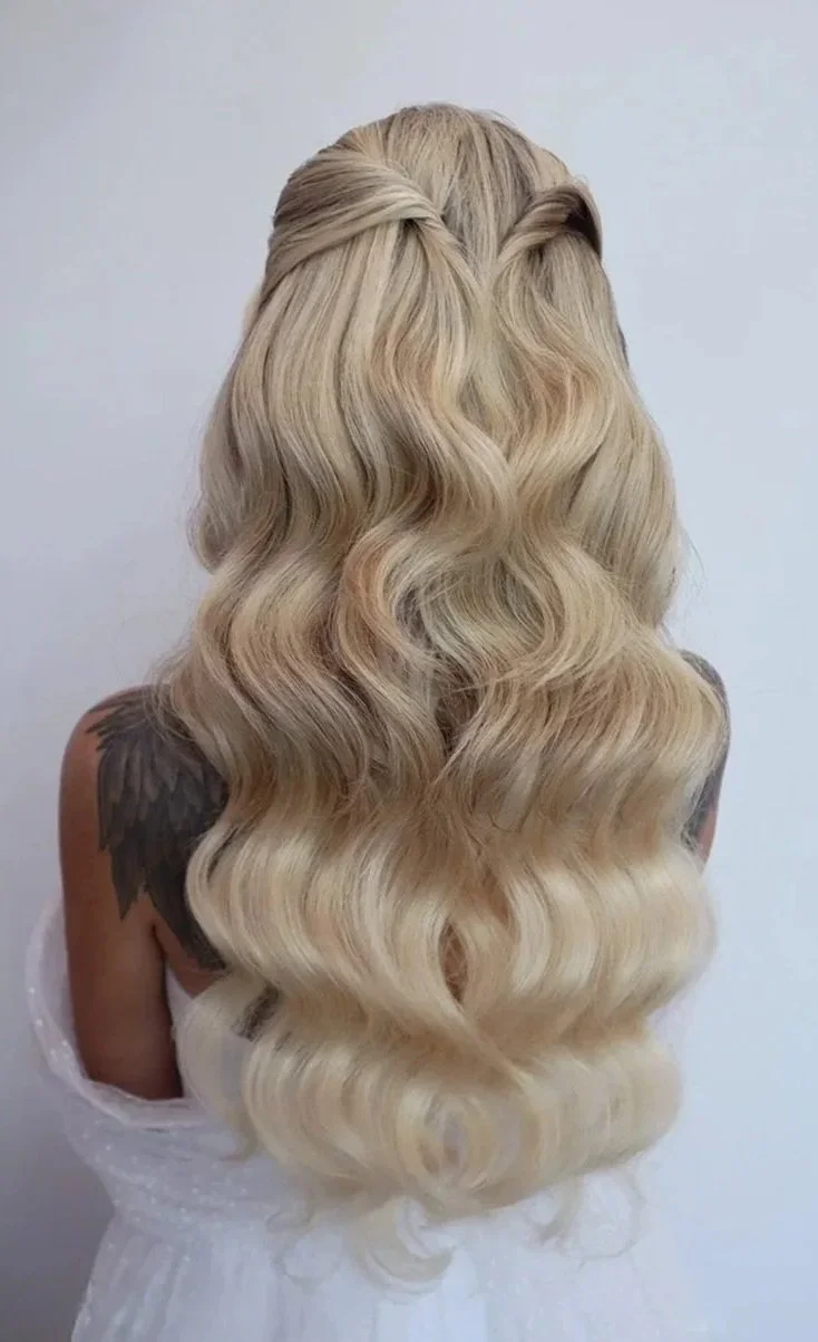 Back view of a woman with long, wavy blonde hair styled in loose waves.