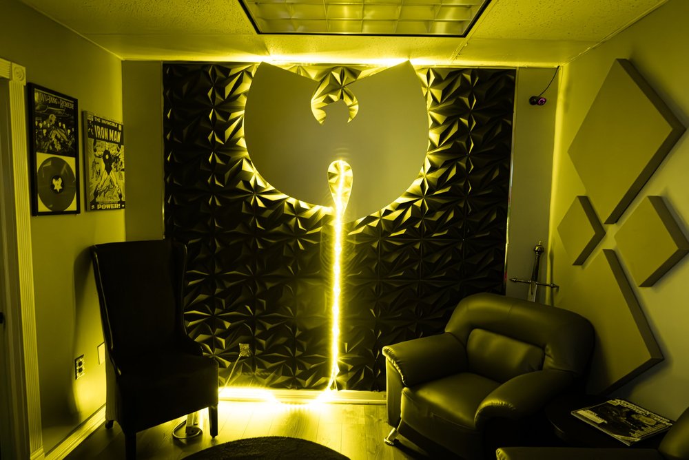 Studio lounge with a backlit Wu-Tang Clan logo wall and leather chairs