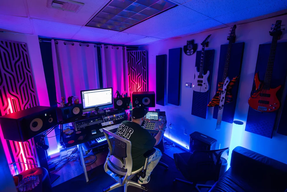 The control room after dark, lit purple and blue, with guitars on the wall