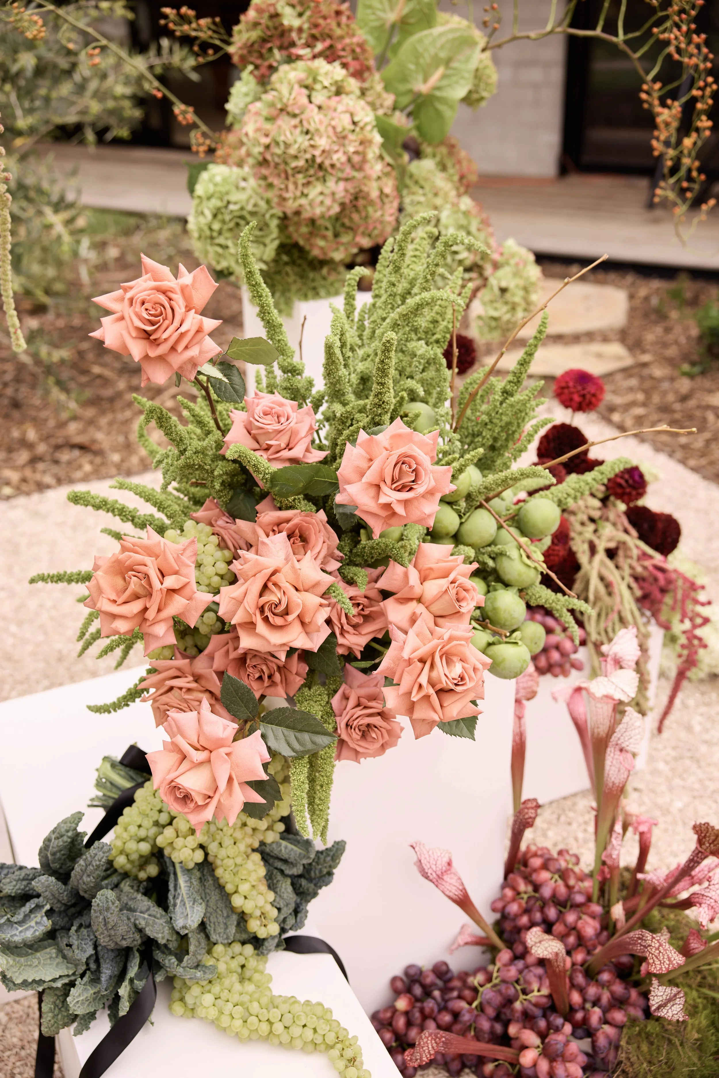 Colorful floral arrangement featuring peach roses, green berries, and various greenery.