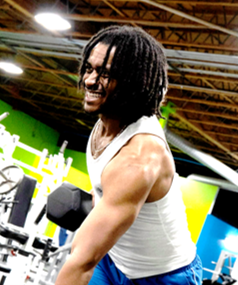 Man with dreadlocks smiling, working out at gym with weights.