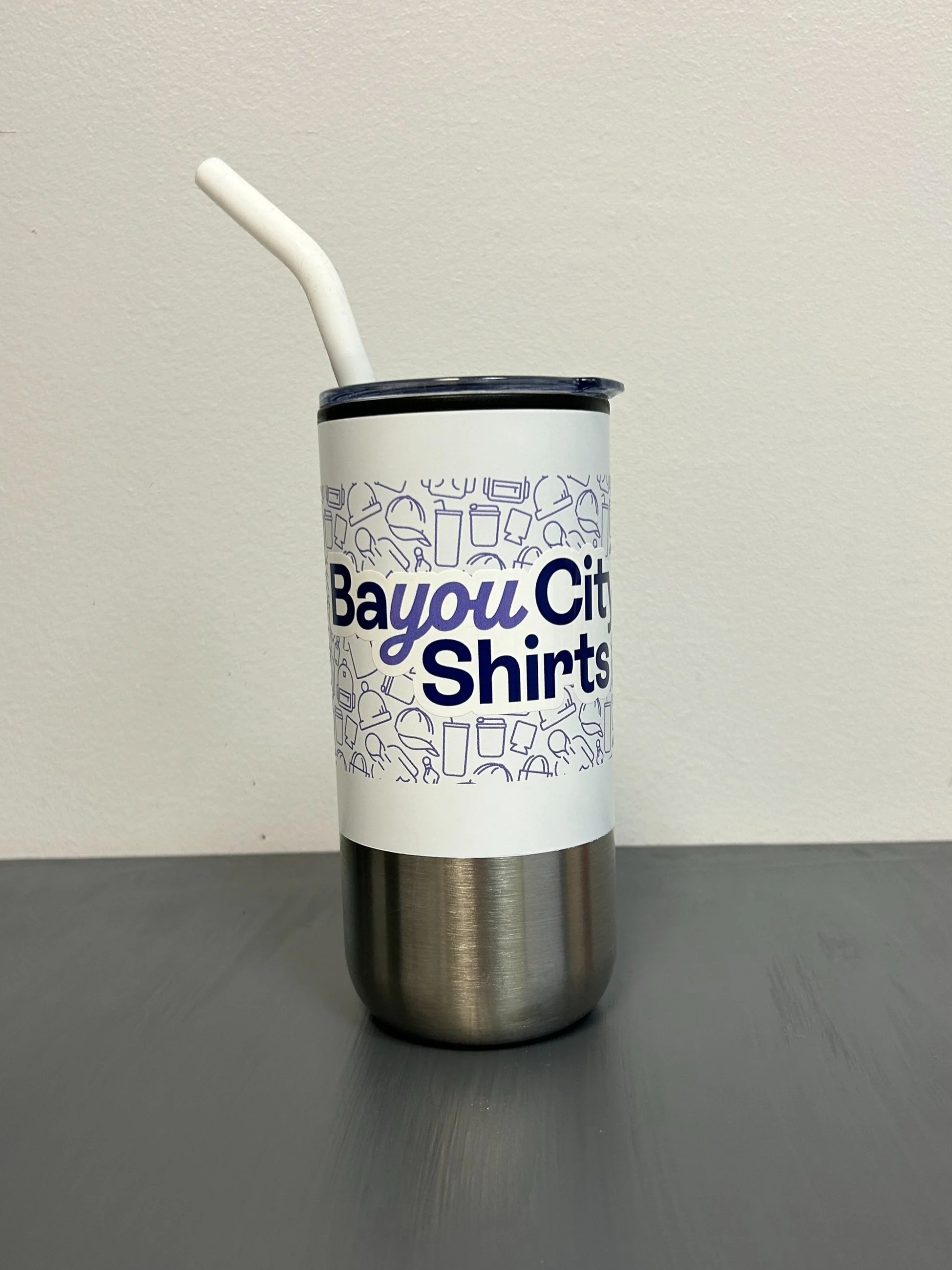 Stainless steel tumbler with white lid and straw, featuring a "Bayou City Shirts" logo.