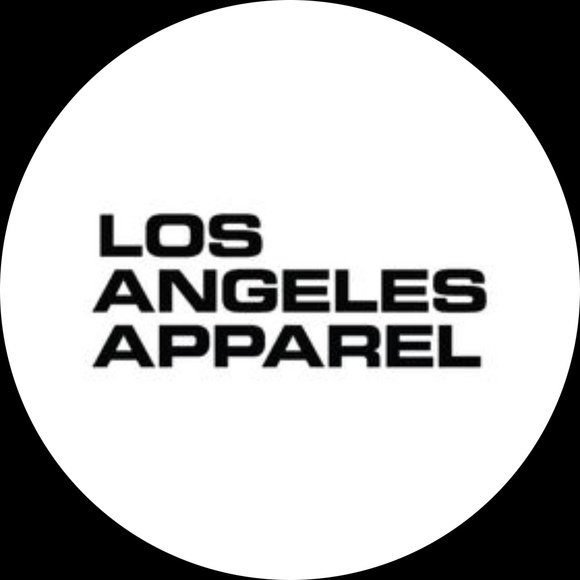 A modern, minimalist building on a grassy hill with snow-covered mountains in the background under a cloudy sky.