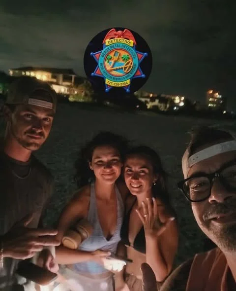 Four people taking a selfie at night on a beach, with a lighthouse and coastal buildings in the background, and a circular badge overlay with a detective emblem.
