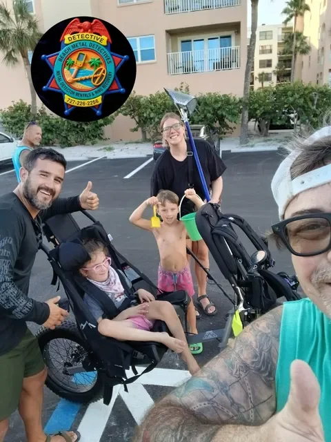 Family and friends taking a selfie in a parking lot, with a man in sunglasses giving a thumbs-up, a young girl in a stroller, a shirtless boy, and another woman holding a rake. An badge for the Brevard County Sheriff's Office Beach Metal Detectives is superimposed on the image.