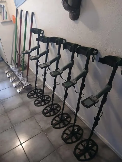 Golf clubs and golf carts lined up against a wall in an indoor setting.