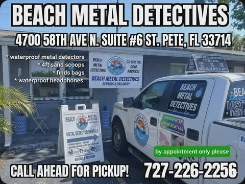 Sign for Beach Metal Detectives featuring contact information, a pickup call-to-action, and a vehicle with company branding, with trees and building in background.