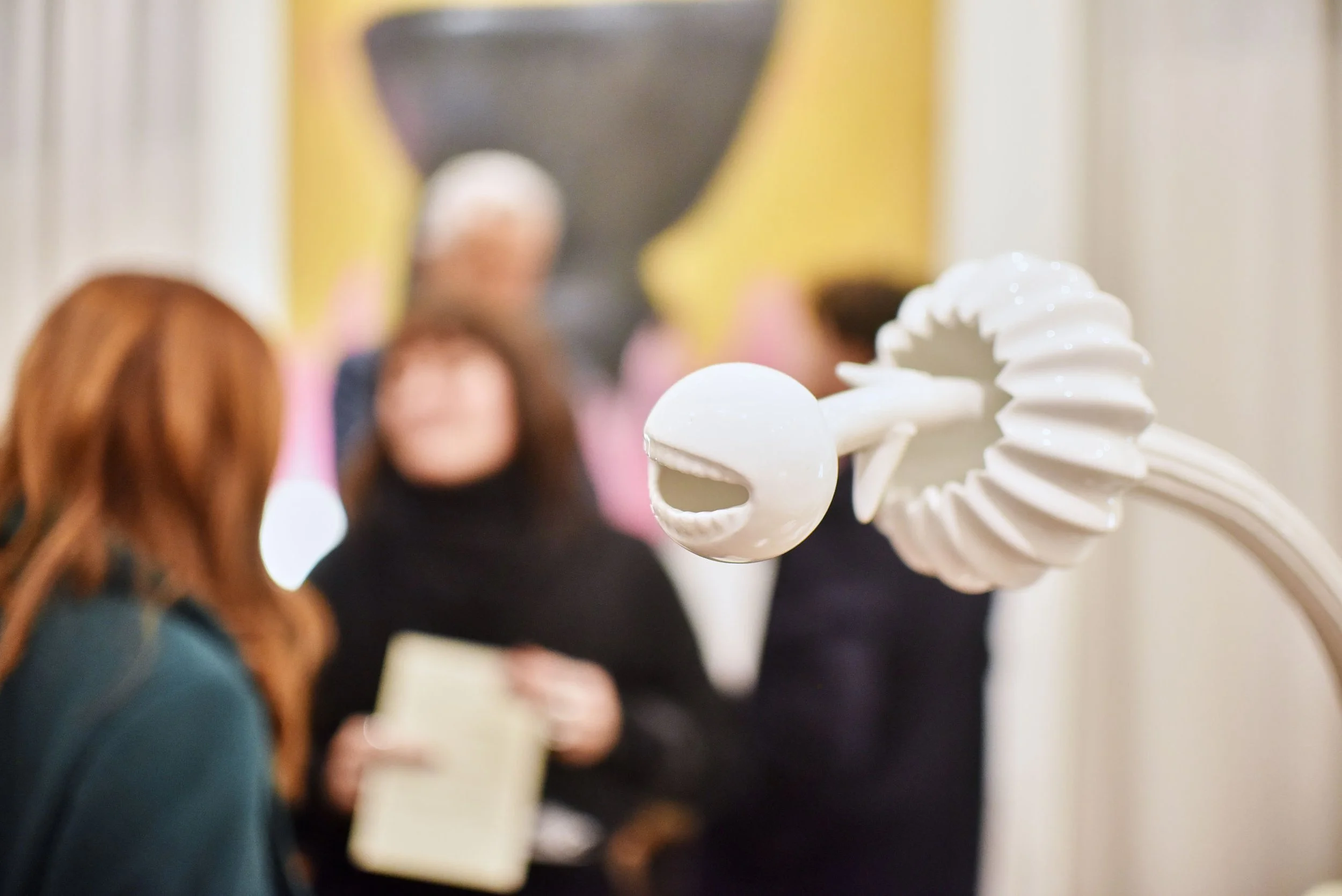 Scultura di un centauro in ceramica bianca davanti a un gruppo di persone in un museo o galleria d'arte.
