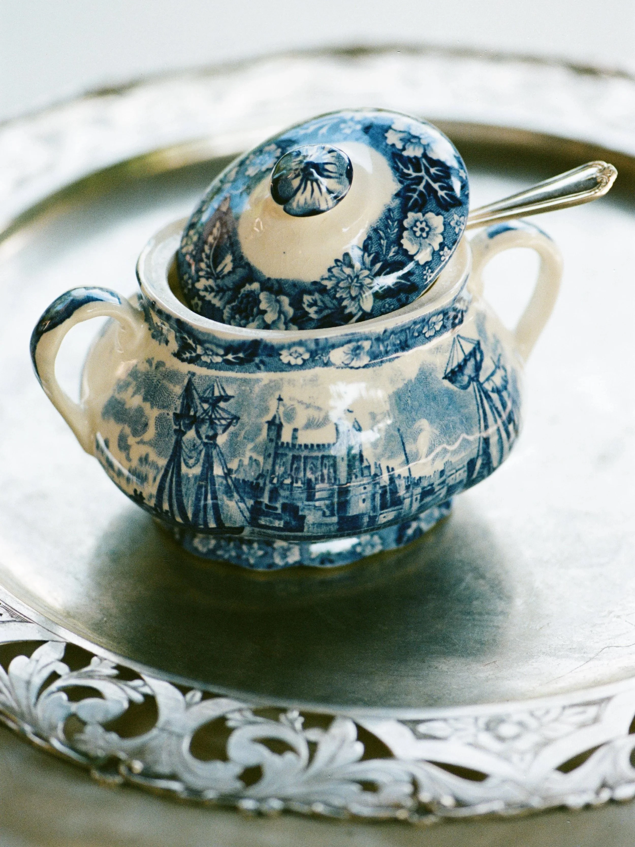 Tazza di porcellana decorata con disegni blu e bianchi, posizionata su un piatto d'argento intagliato.