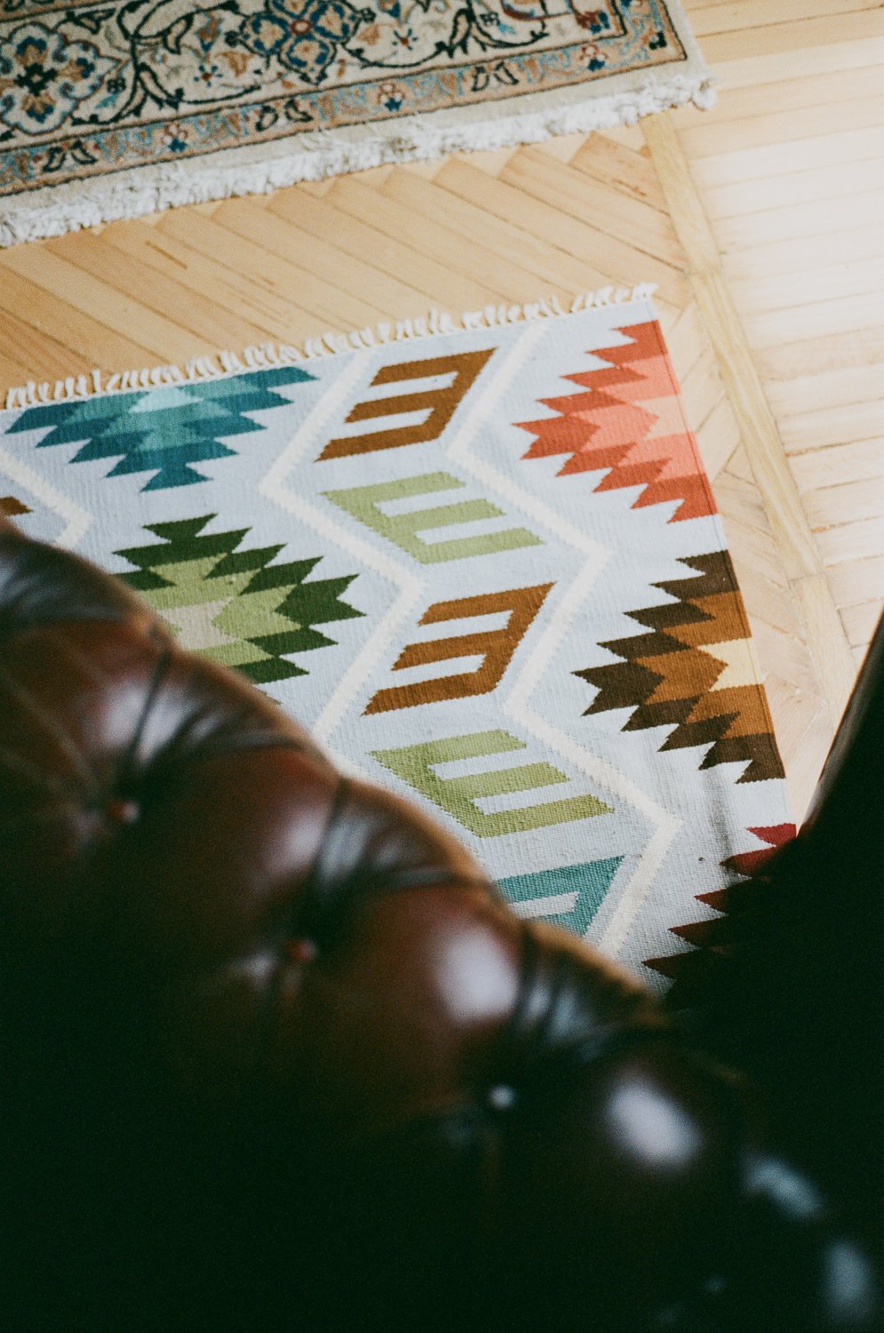 Tappeto con motivi geometrici in vari colori su un pavimento in legno.