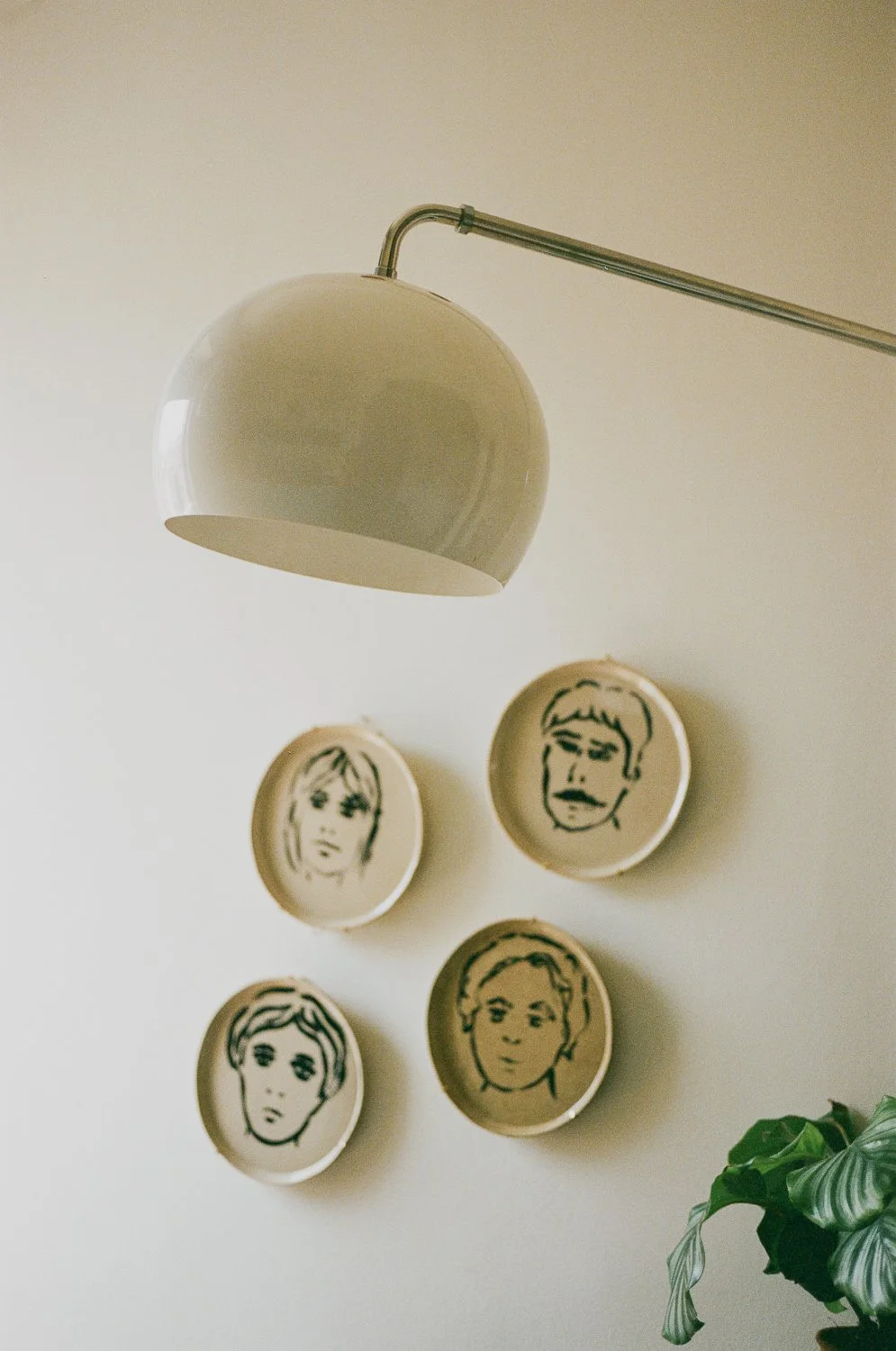 Luce da soffitto bianca in stile rétro e piatti decorativi con volti in bianco e nero sulla parete