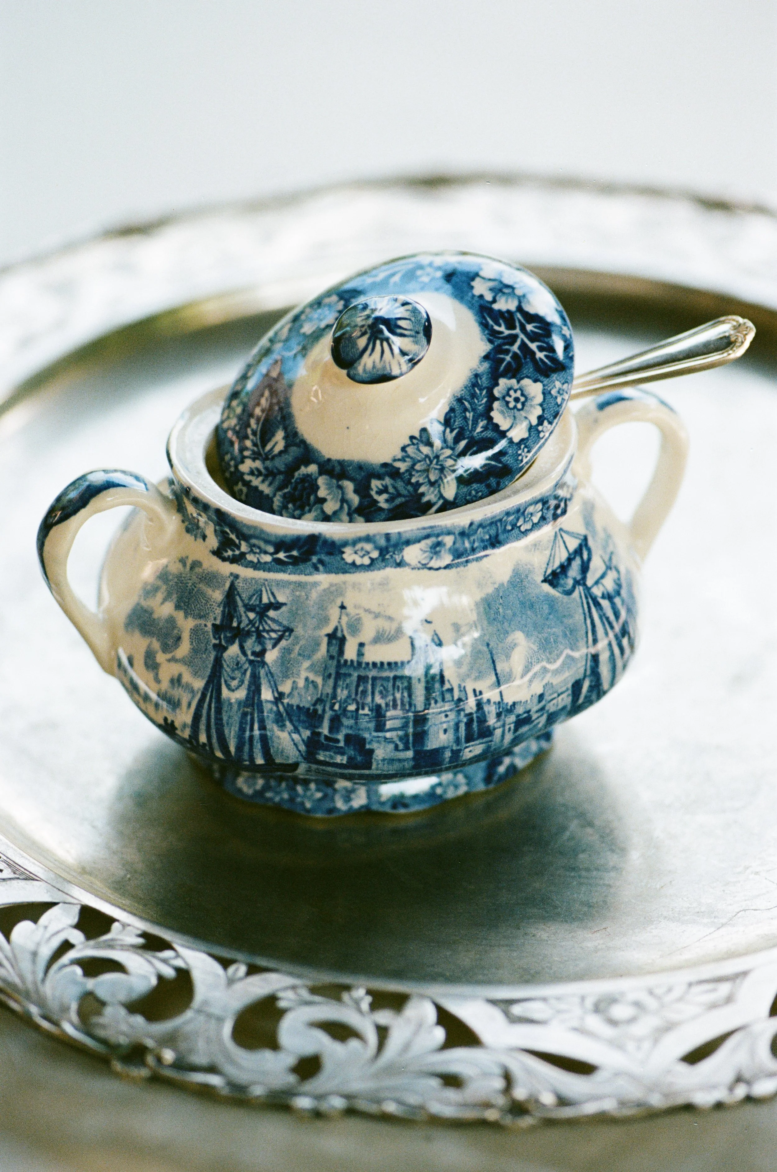 Tazza di porcellana decorata con disegni blu e bianchi, posizionata su un piatto d'argento intagliato.