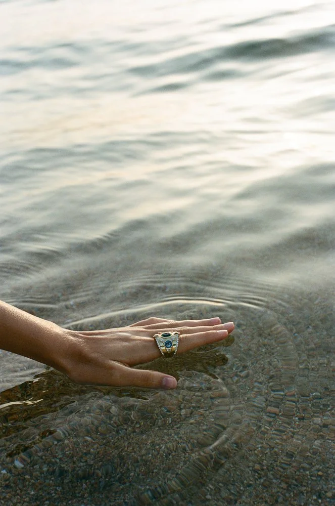 Mano con anello che tocca l'acqua di uno specchio d'acqua tranquillo
