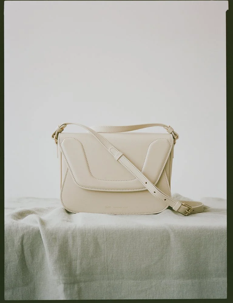 borsa a tracolla beige su una superficie di tessuto chiaro