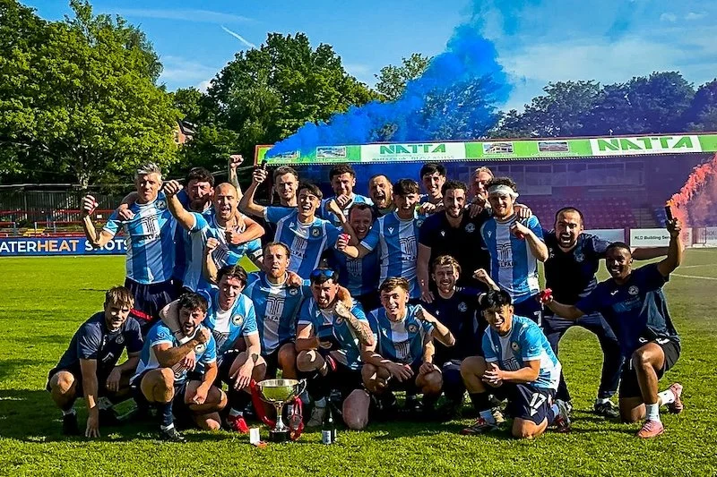 Whitehill &amp; Bordon FC team with the ADFA Saturday Intermediate Cup trophy as players celebrate with champagne and smoke flares, May 2026