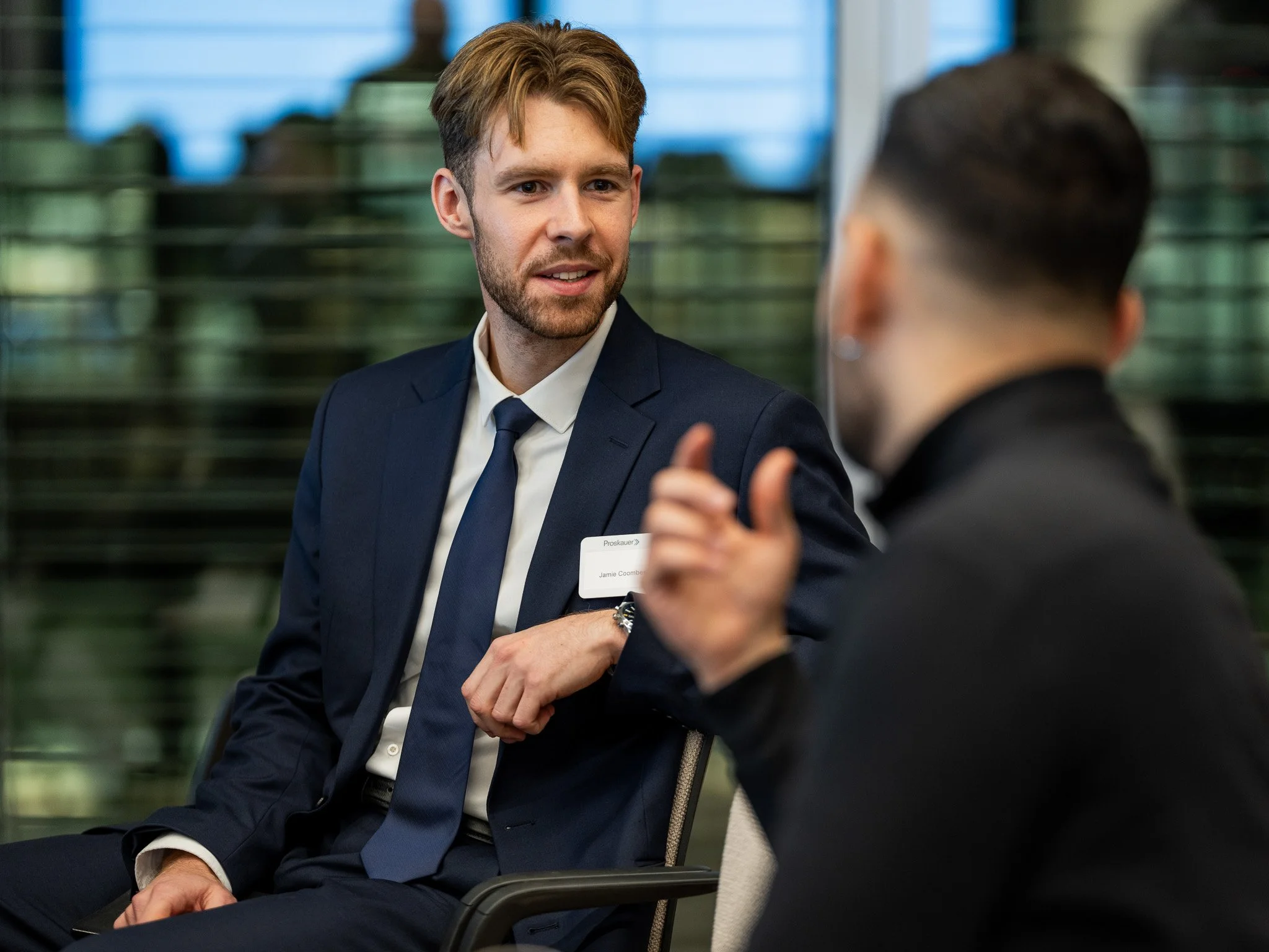 Two men in suits having a conversation in an office or conference room.