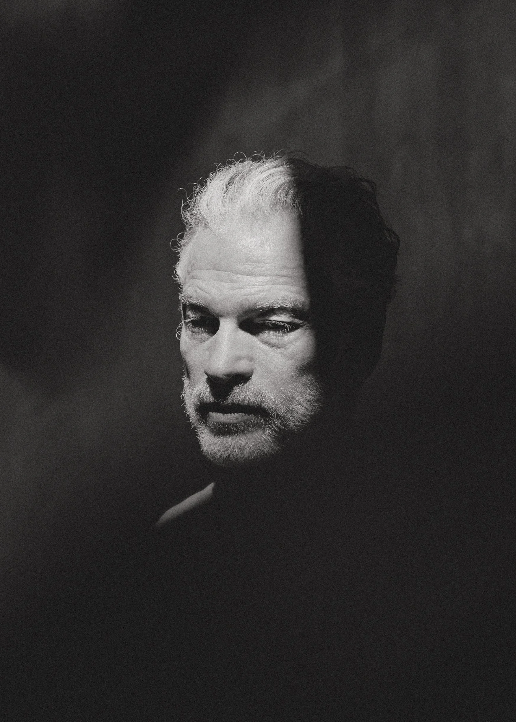 Retrato de estudio en blanco y negro de un hombre mayor, iluminación dramática dividiendo el rostro en luz y sombra.