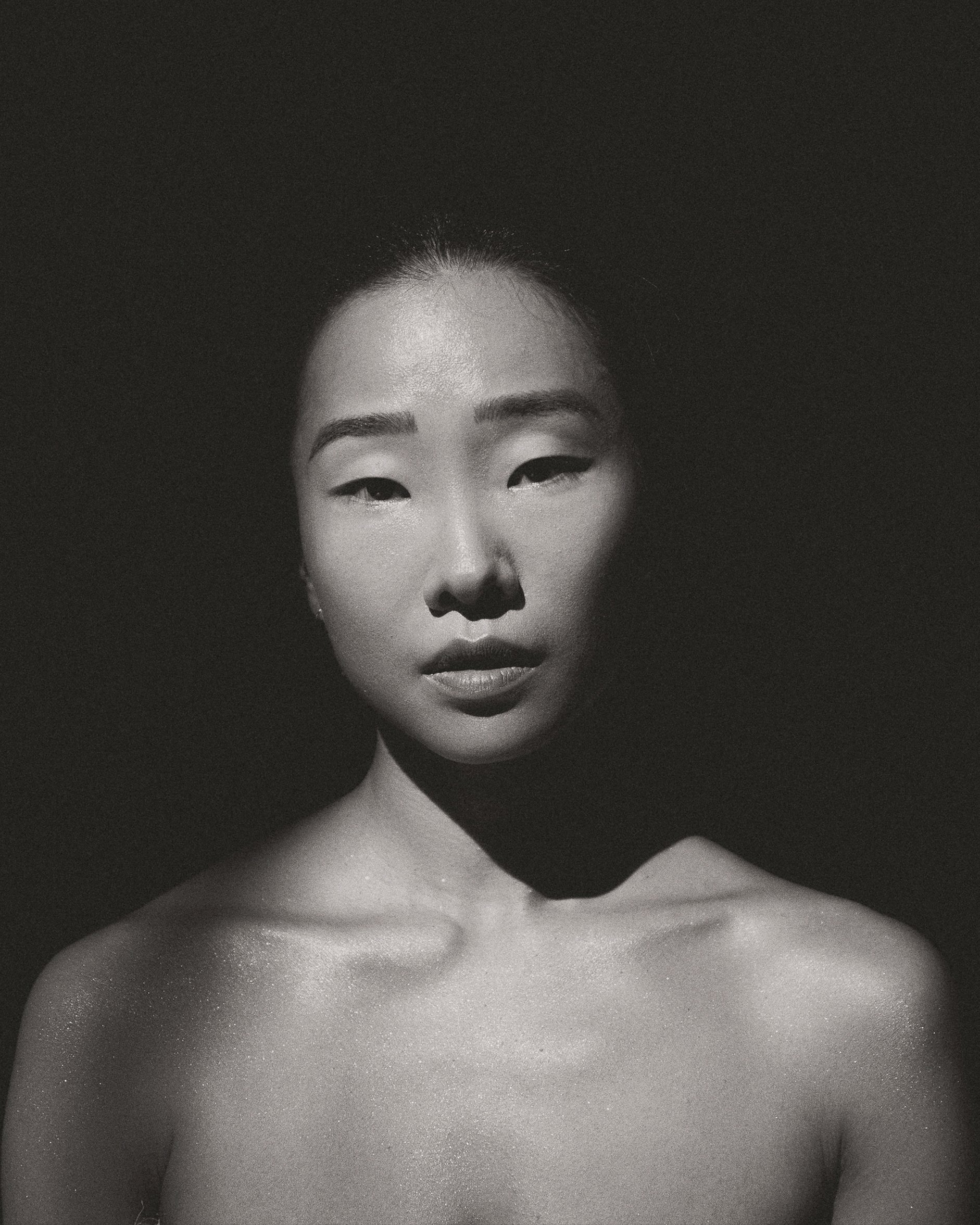 Retrato en blanco y negro del rostro de una mujer asiática con sombras duras de estudio.